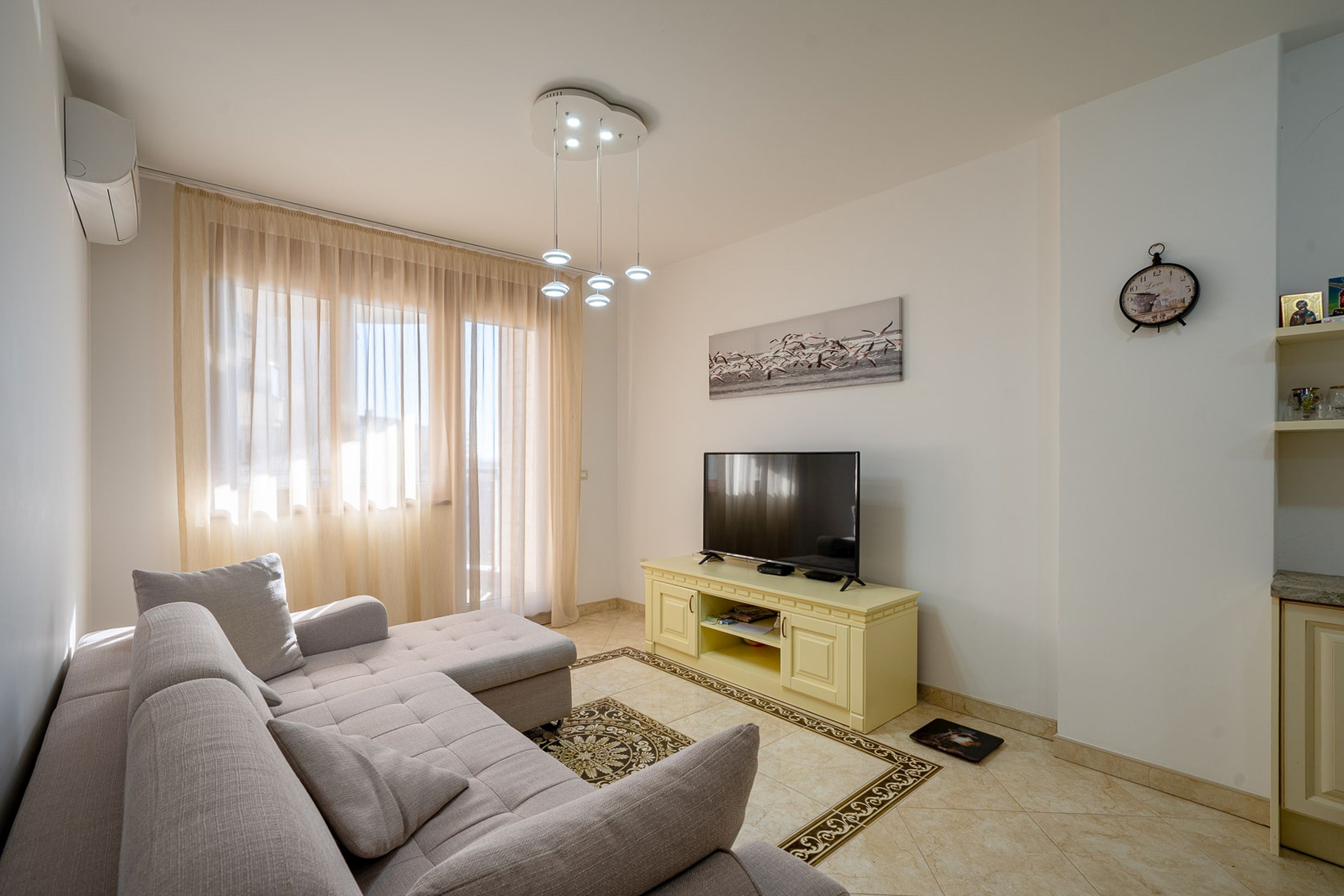 Bright living room with a corner sofa and TV area in an apartment for sale, Becici, Montenegro.