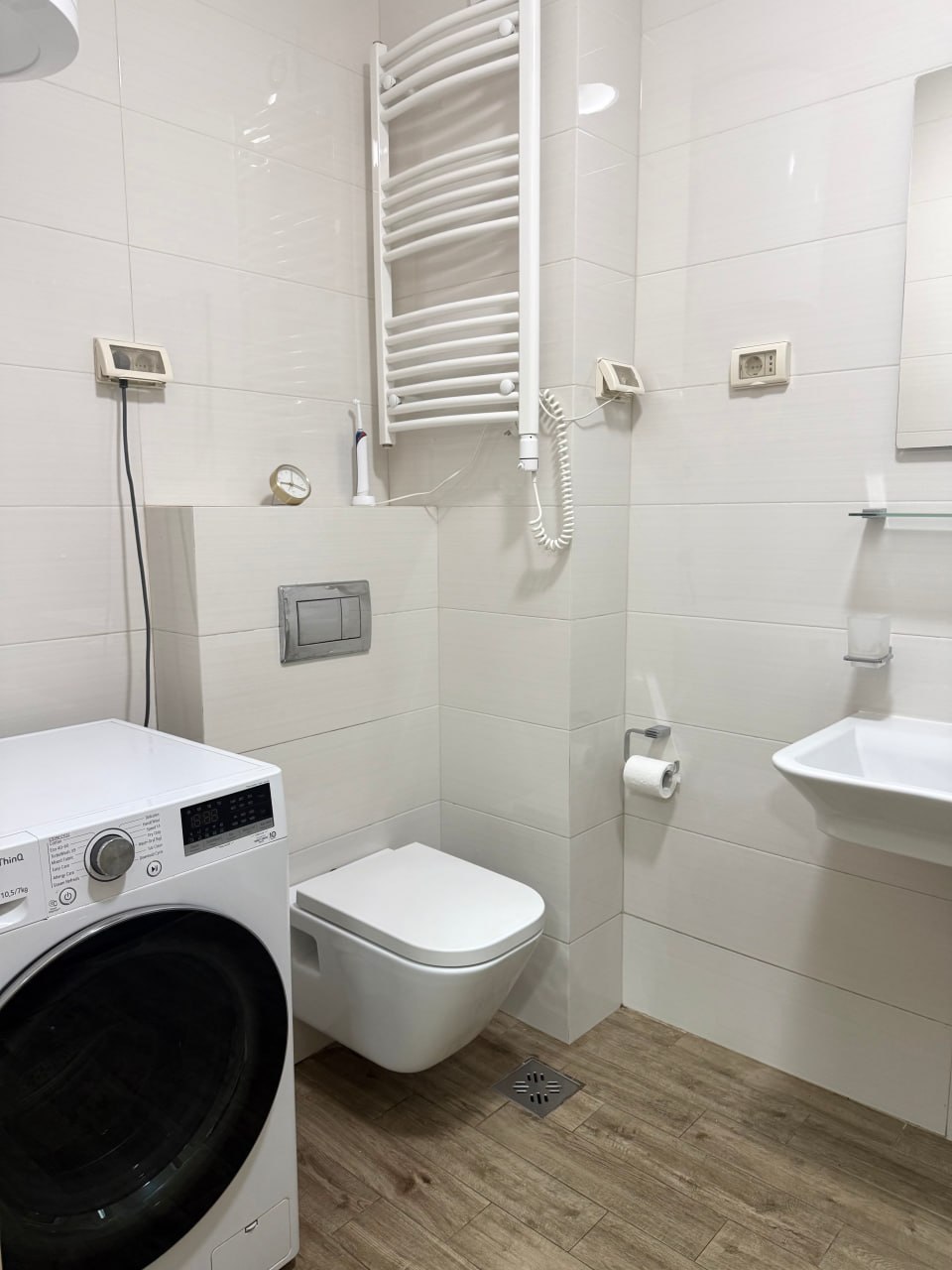 Modern bathroom in an apartment in Podgorica, Montenegro: white tiles, wall-hung toilet, and washing machine.