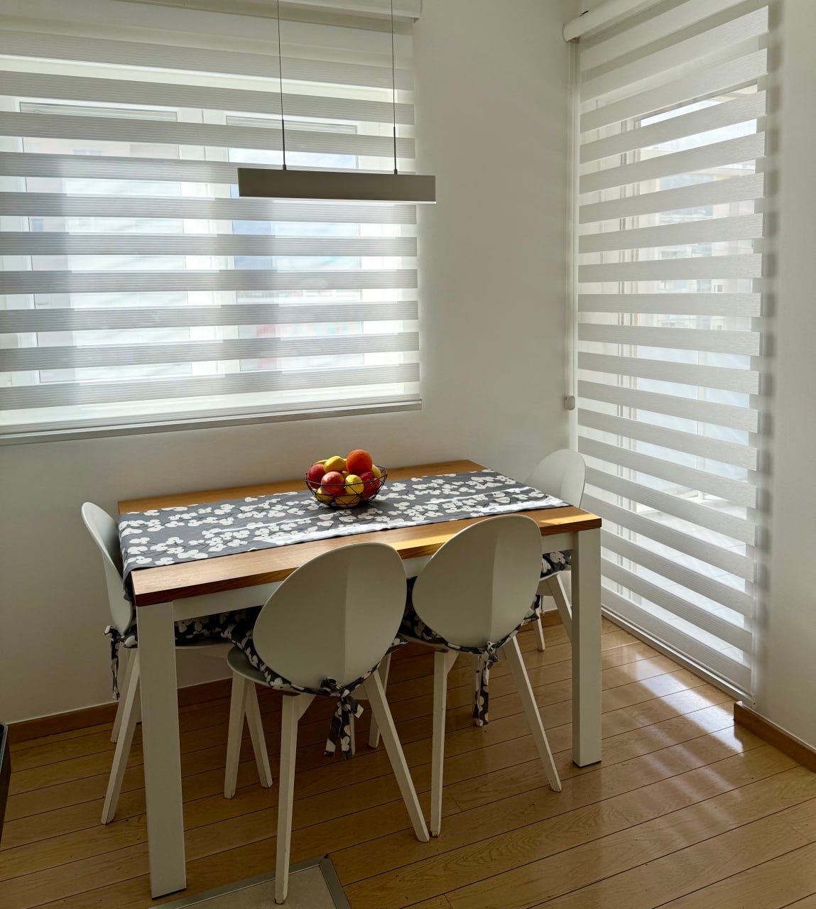 Dining area with a wooden table and white chairs in a modern apartment, Podgorica, Montenegro.