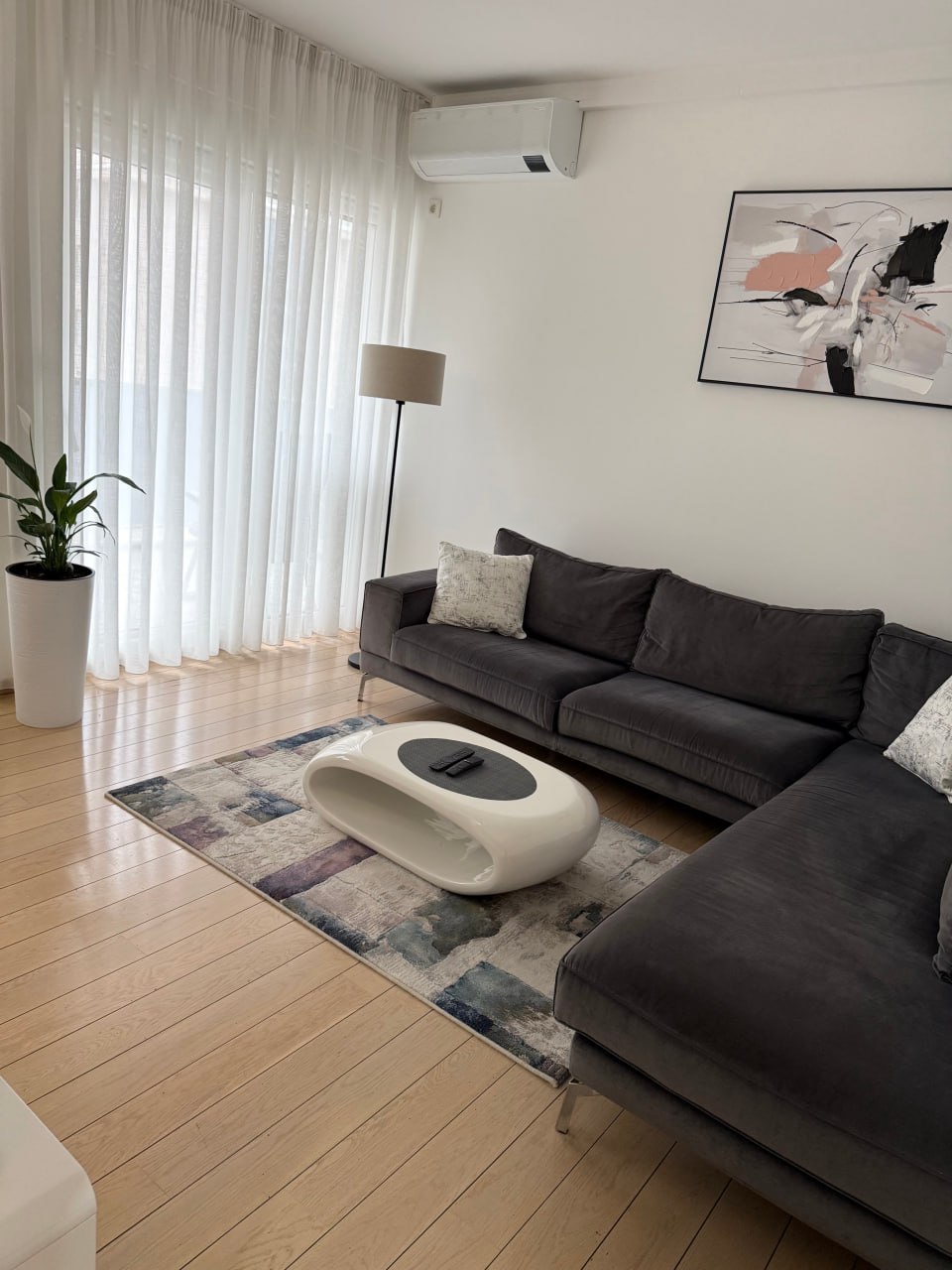 Modern living room in an apartment in Podgorica, Montenegro: gray sofa, designer coffee table, and bright interior.