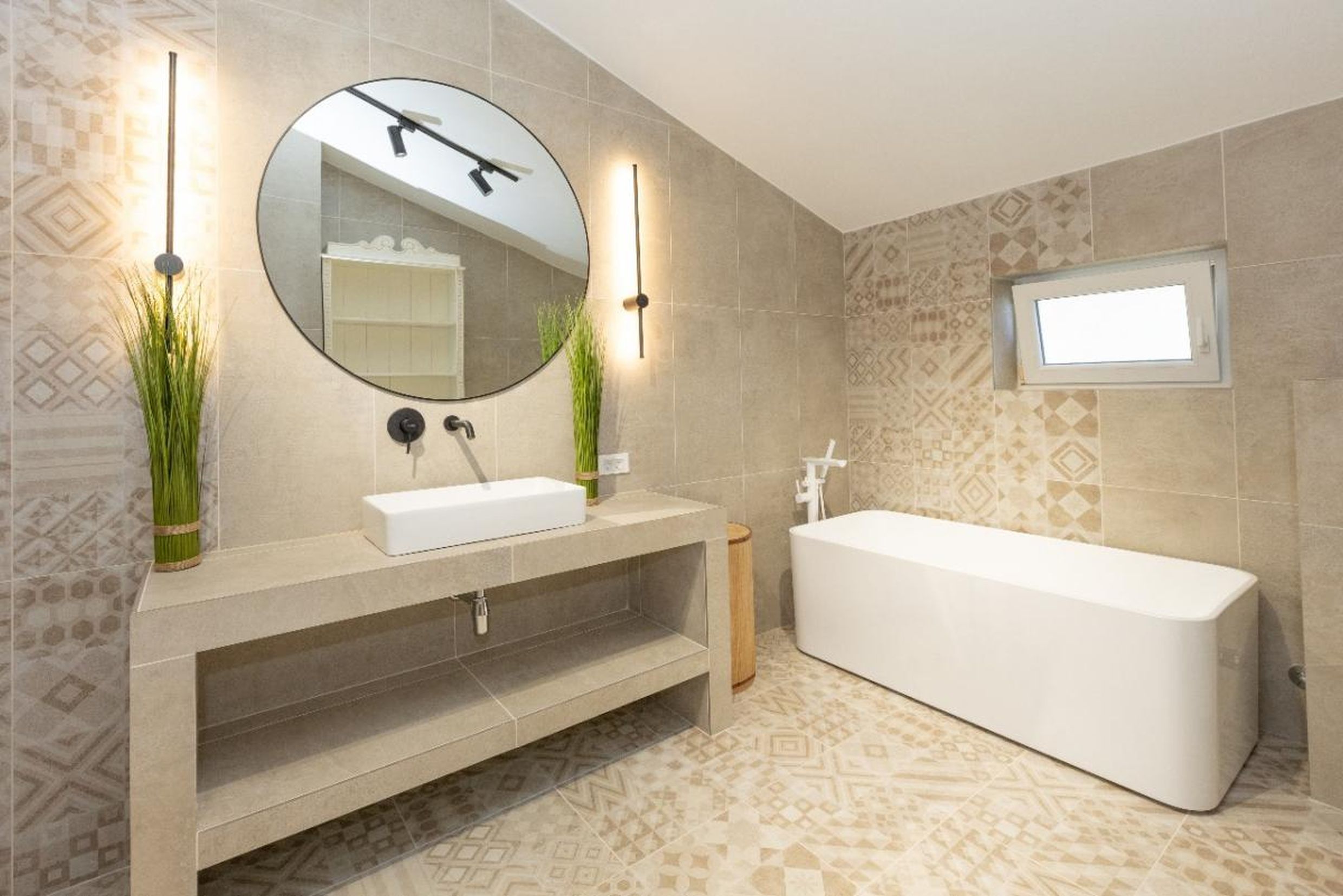 Modern bathroom with a white bathtub and stone countertop in a house in Tivat, Montenegro. Ornamental tile.