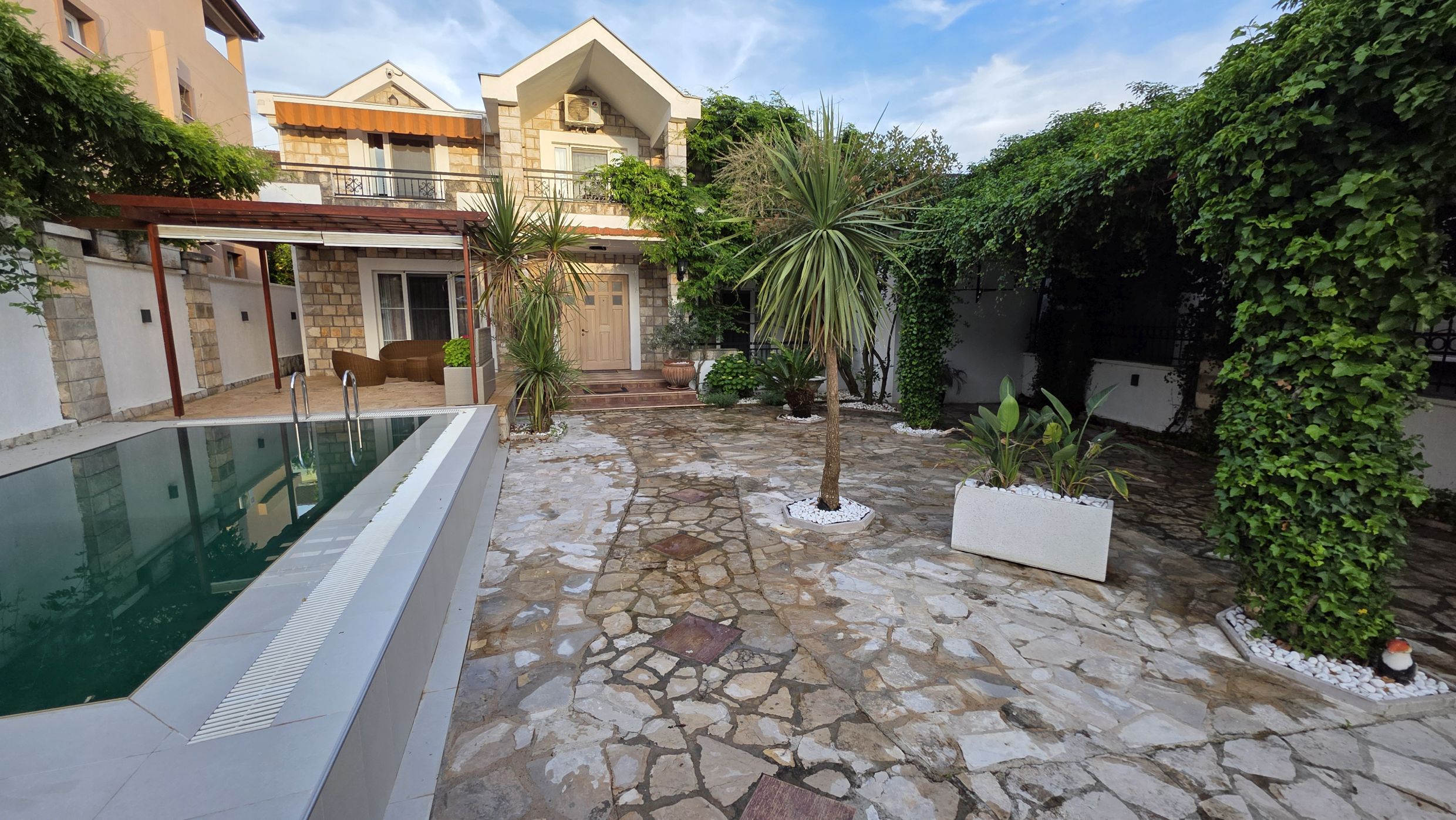 Two-story villa with a pool and a green garden in Tivat, Montenegro: stone facade and a cozy terrace.