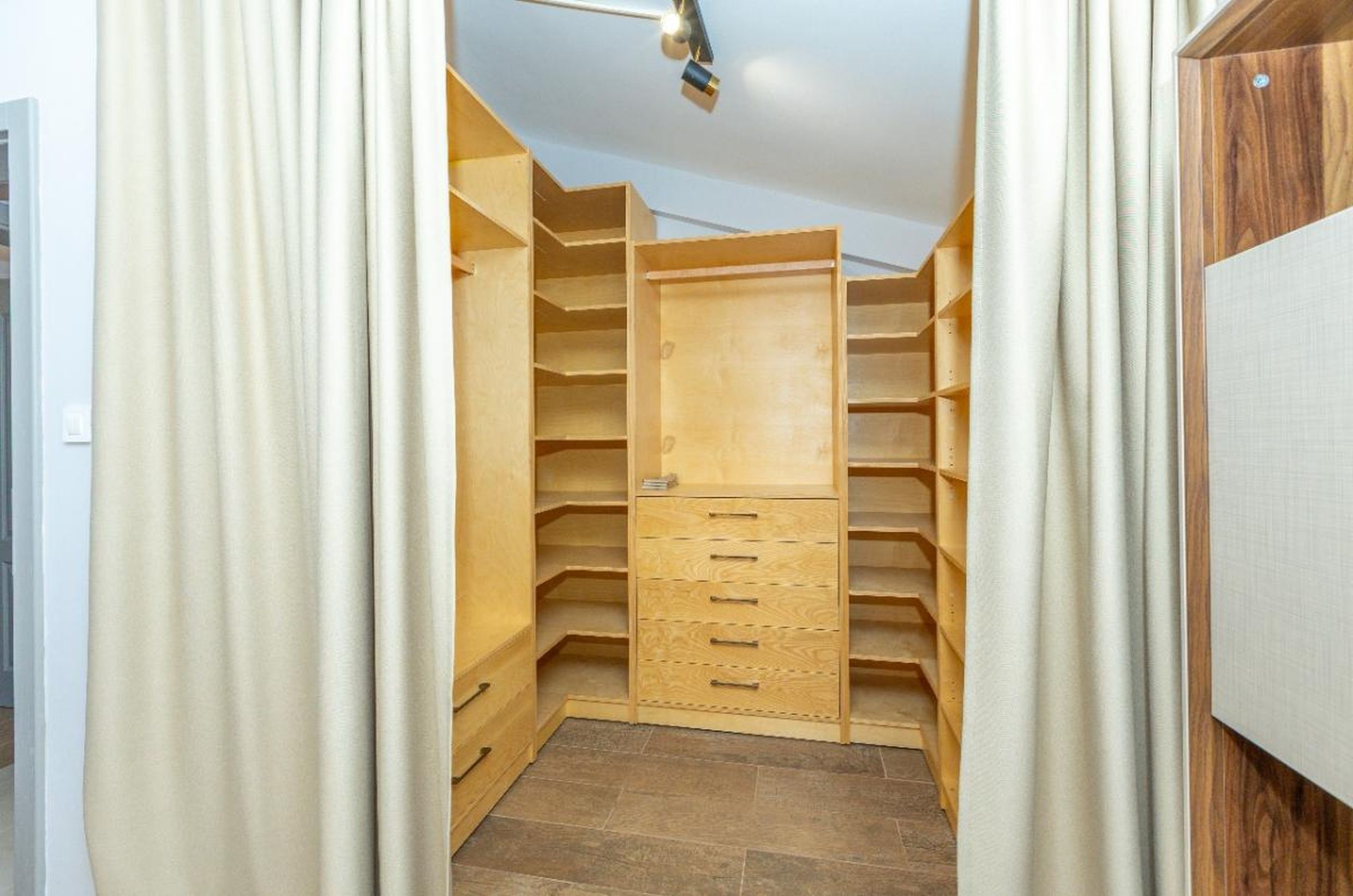 Spacious walk-in closet with wooden shelving and a dresser in a house in Tivat, Montenegro.