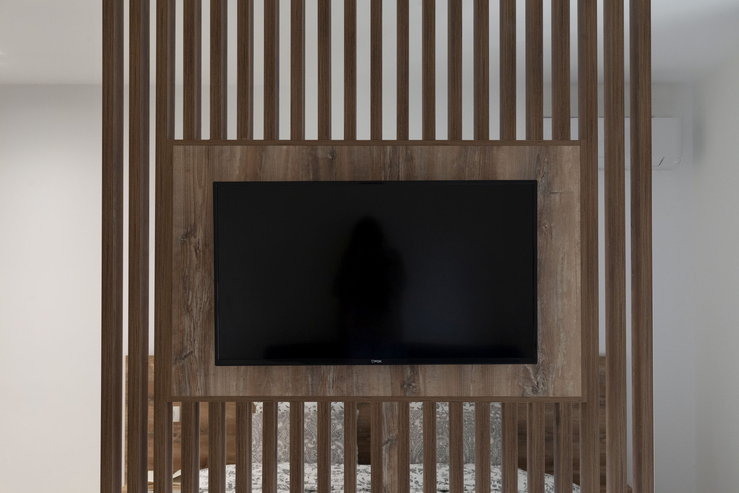 Modern bedroom in an apartment in Kotor, Montenegro: TV on a decorative wooden slatted partition.