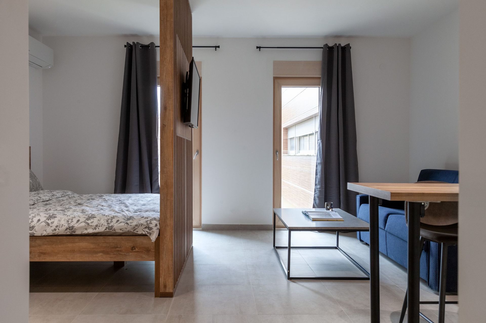 Modern living room with a bed and seating area in an apartment, Kotor, Montenegro: wooden partition and access to the balcony.