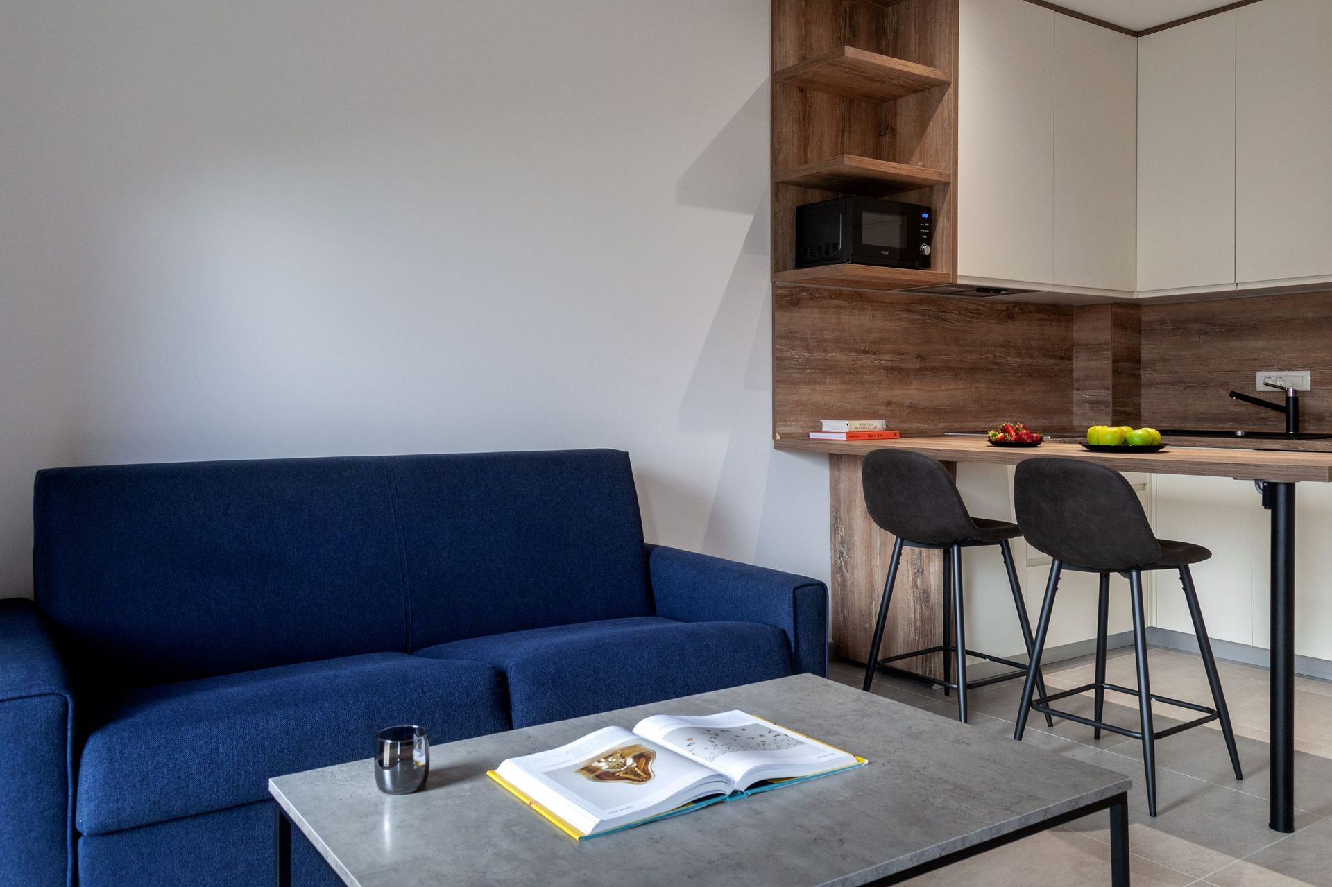 Modern living room with a blue sofa and kitchen area in an apartment in Kotor, Montenegro: stylish interior and a bar counter