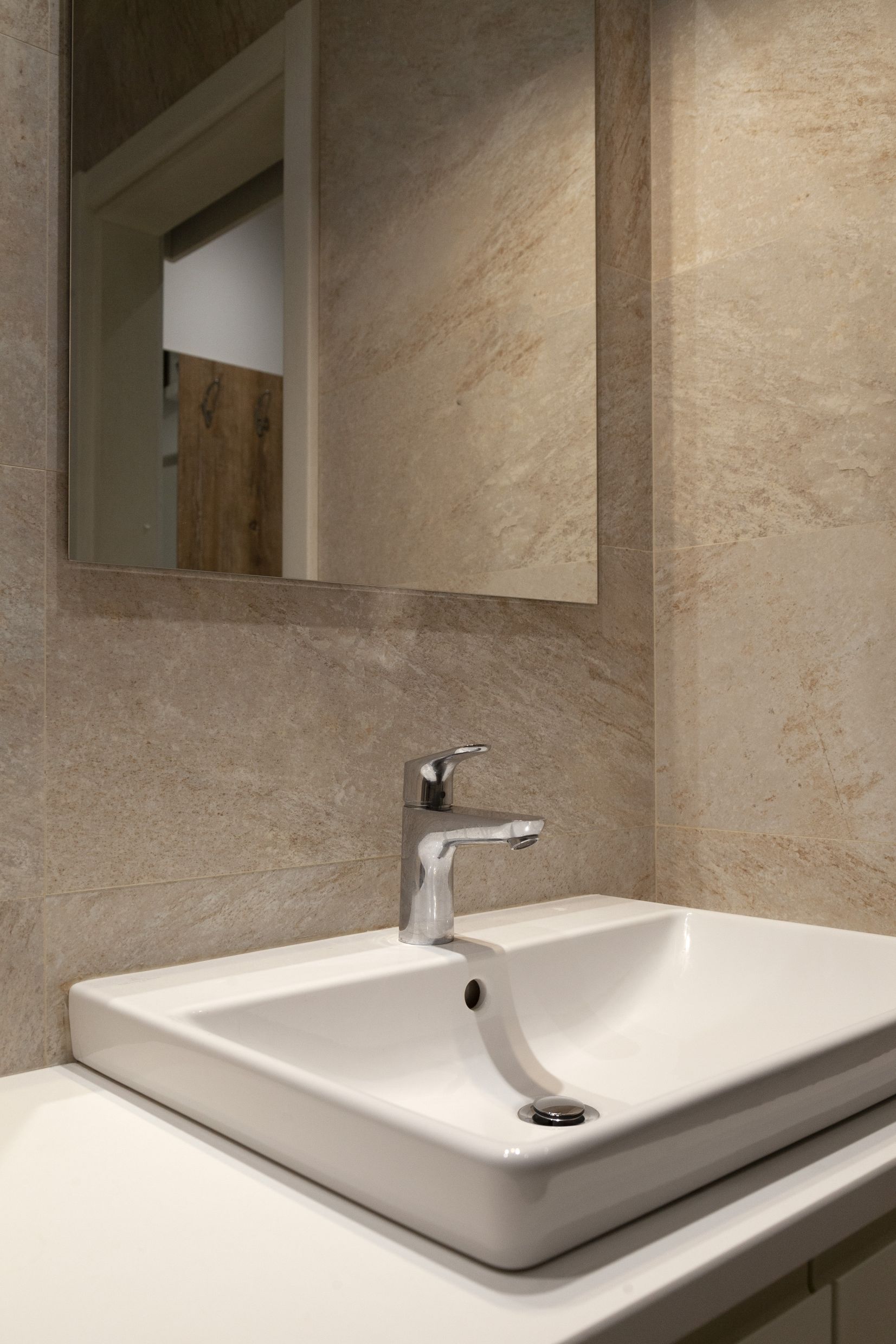 Modern bathroom with a white sink and beige tiles in an apartment in Kotor, Montenegro.