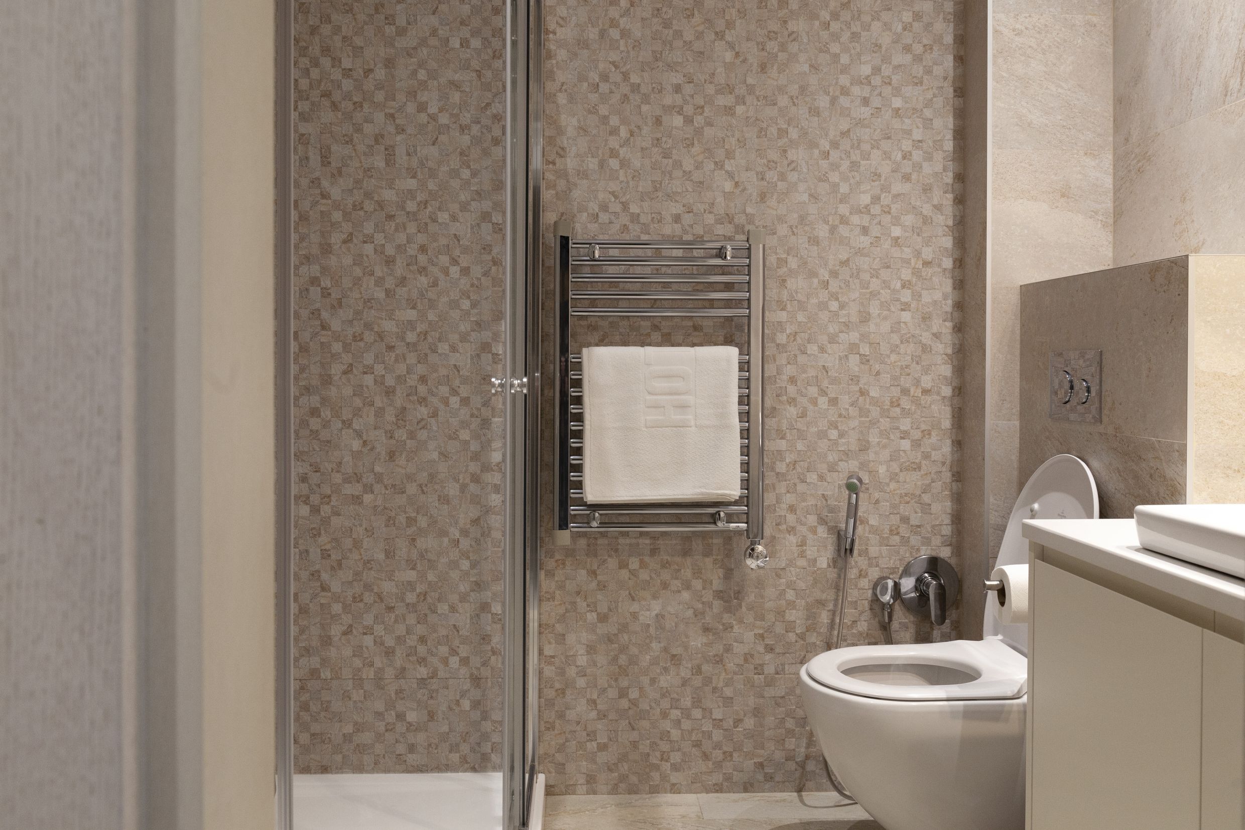 Modern bathroom in an apartment in Kotor, Montenegro: shower cabin, wall-mounted toilet, and towel warmer.