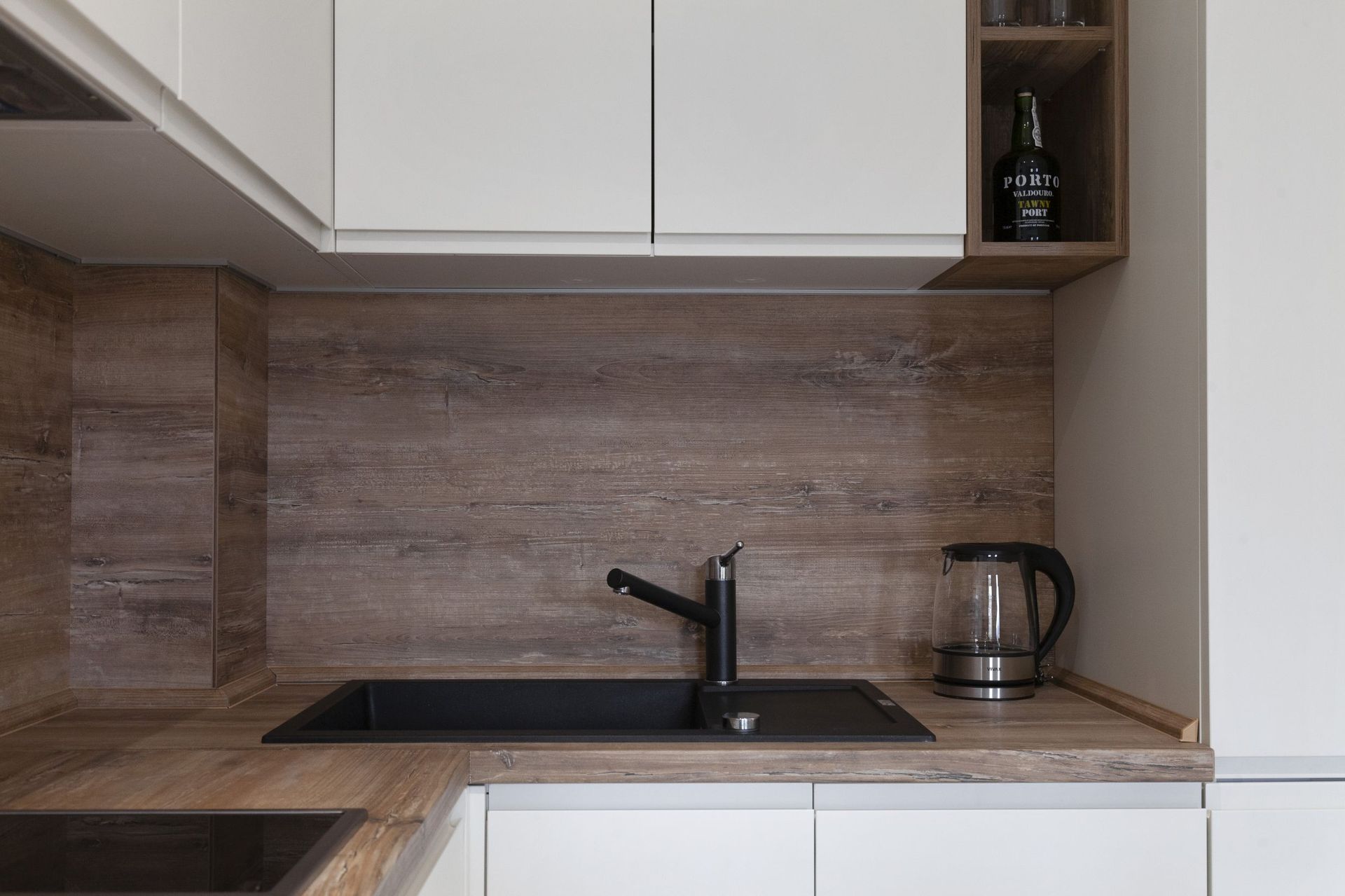 Modern kitchen with white fronts and a wooden countertop in an apartment in Kotor, Montenegro: black sink and faucet.