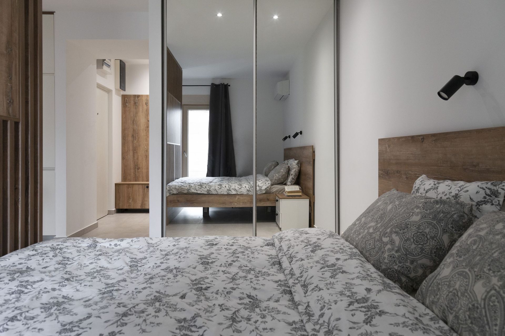 Modern bedroom with a double bed and mirrored sliding wardrobe in an apartment, Kotor, Montenegro.