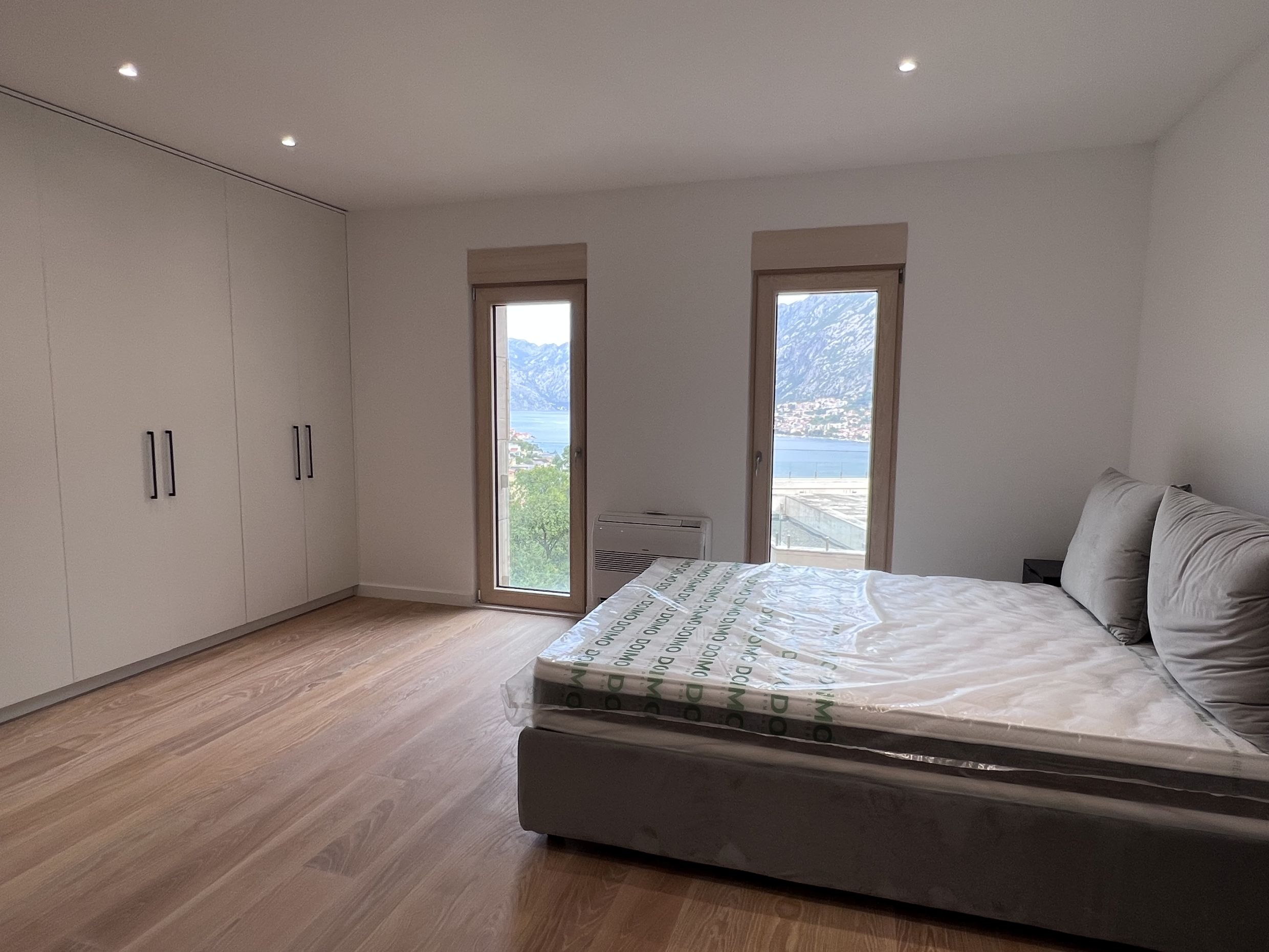 Bedroom in a new apartment in Kotor, Montenegro: double bed, built-in wardrobe, and a view of the Bay of Kotor.