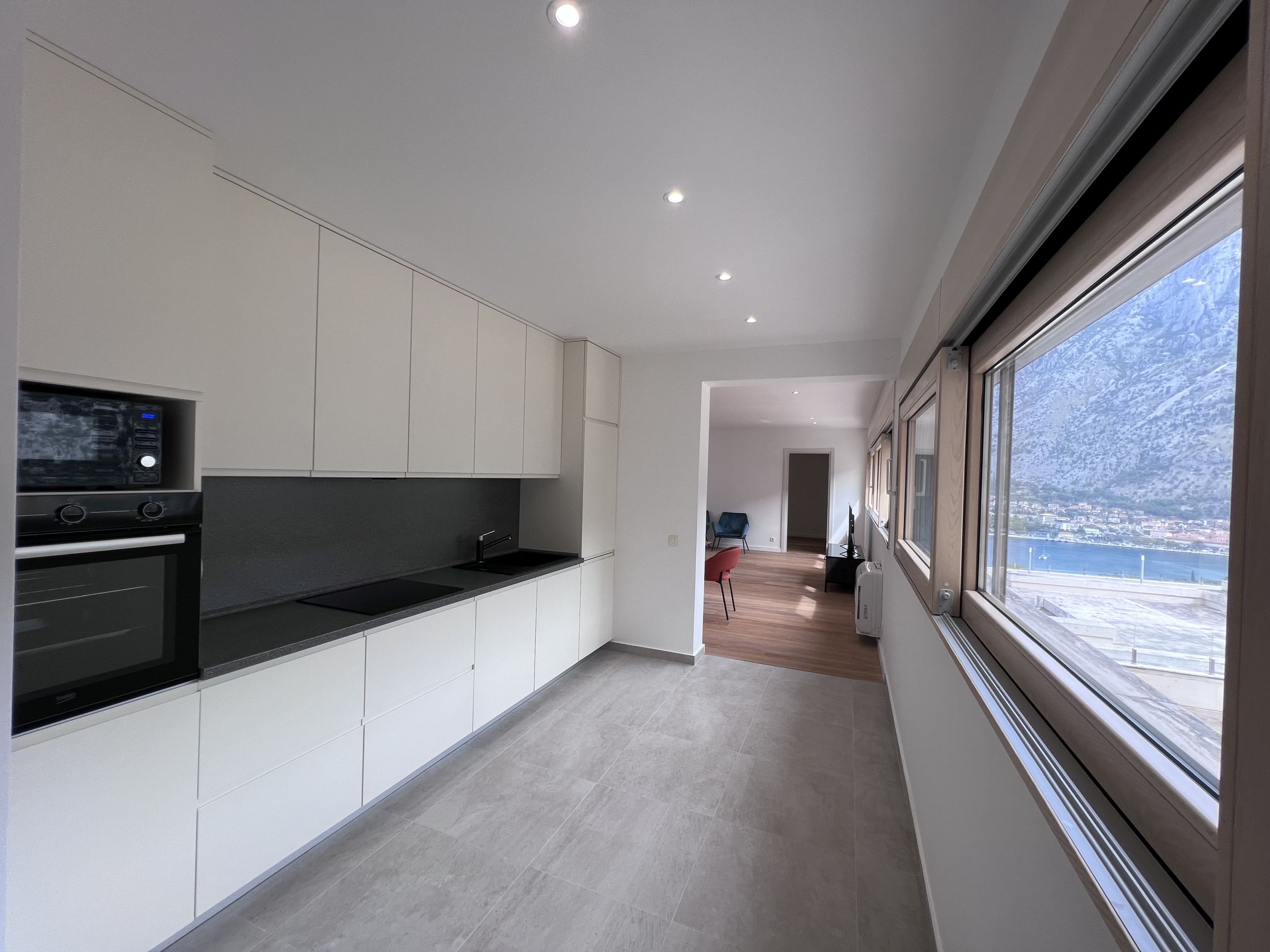 Modern kitchen in an apartment in Kotor, Montenegro, with a bay view, white cabinetry, and built-in appliances.