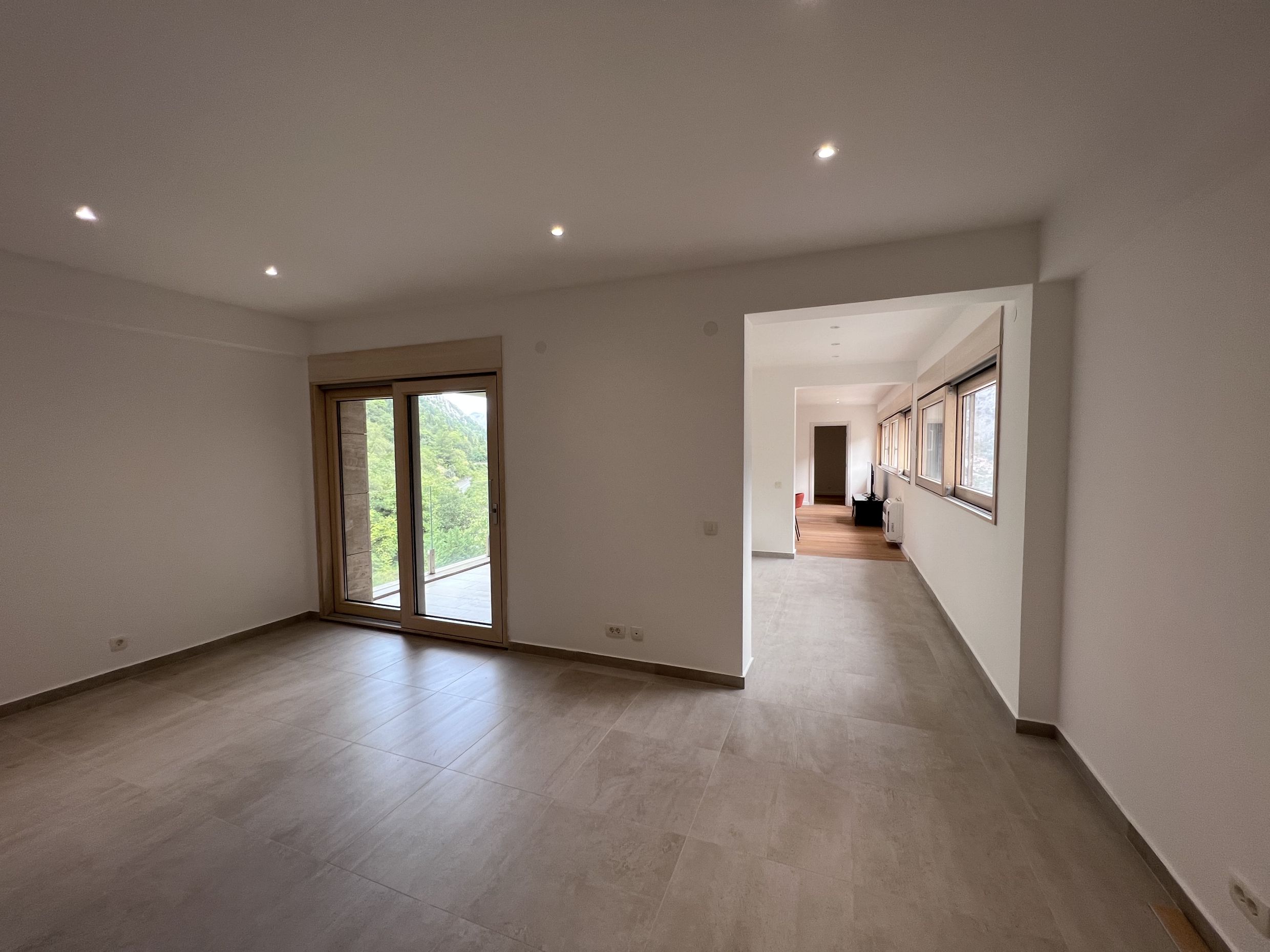 Bright living room with panoramic mountain views in an apartment, Kotor, Montenegro: modern finishes and tiled flooring.