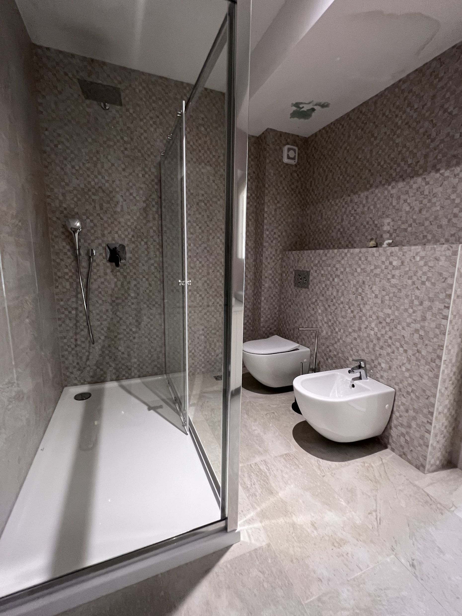 Modern bathroom with a shower cabin, wall-mounted toilet, and bidet in an apartment, Kotor, Montenegro.