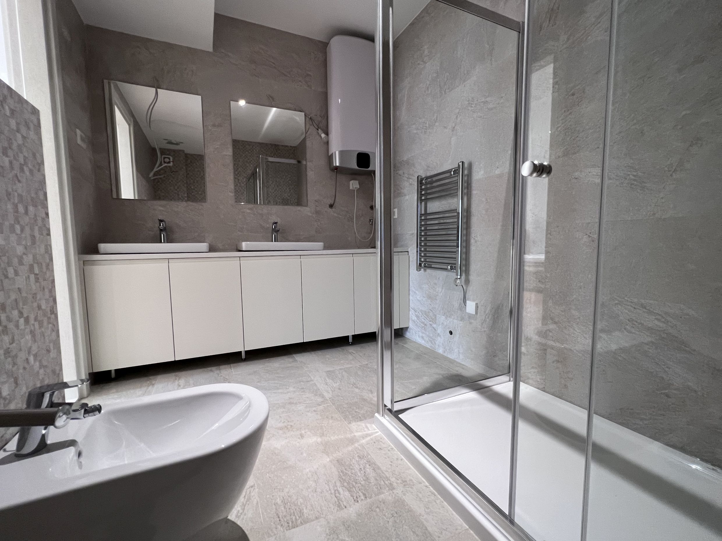 Modern bathroom in an apartment in Kotor, Montenegro: shower cabin, vanity with two sinks, and bidet.