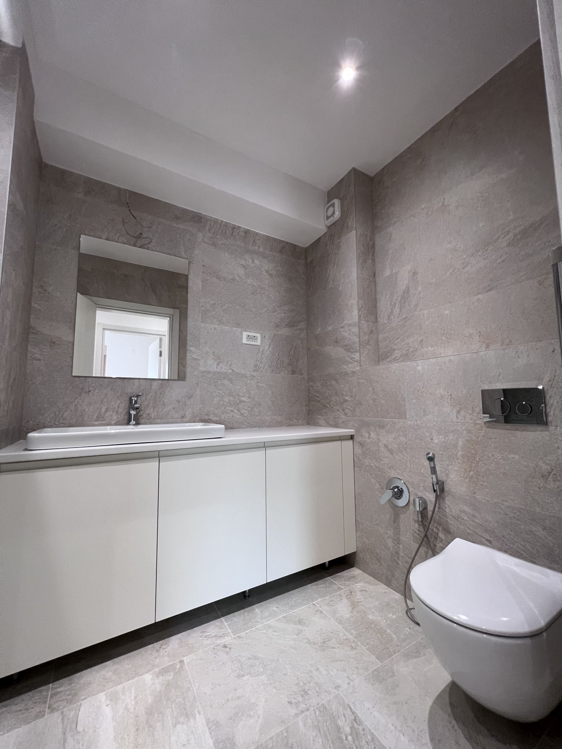 Modern bathroom in an apartment, Kotor, Montenegro: white vanity, vessel sink, and wall-mounted toilet.