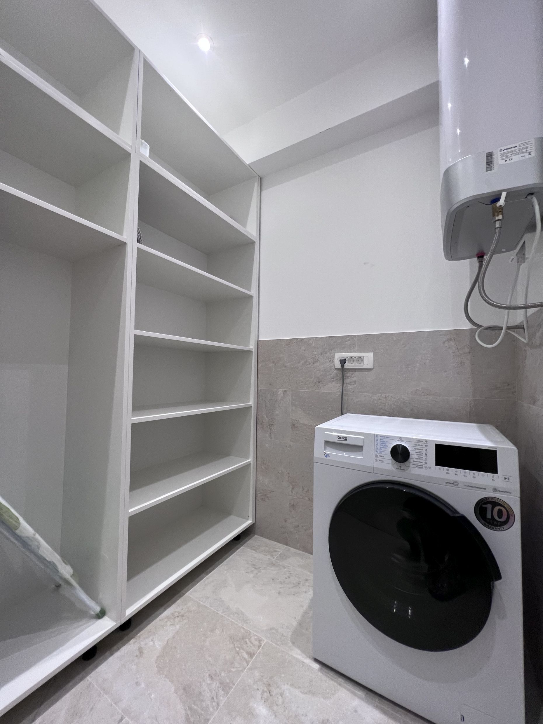 Utility room with white shelving, a Beko washing machine, and a boiler in an apartment, Kotor, Montenegro