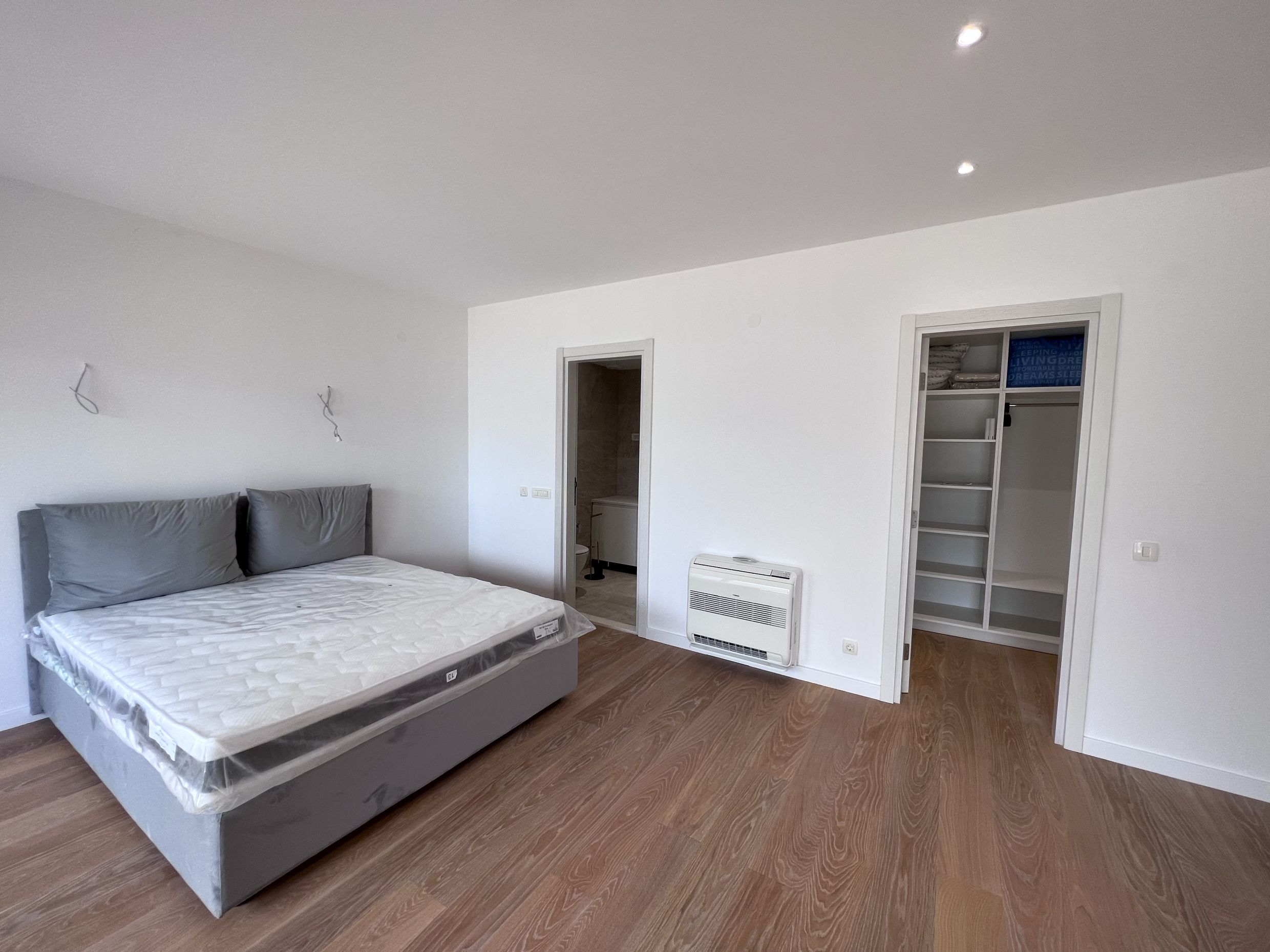 Bright bedroom with a double bed, walk-in closet, and bathroom in a new apartment in Kotor, Montenegro.