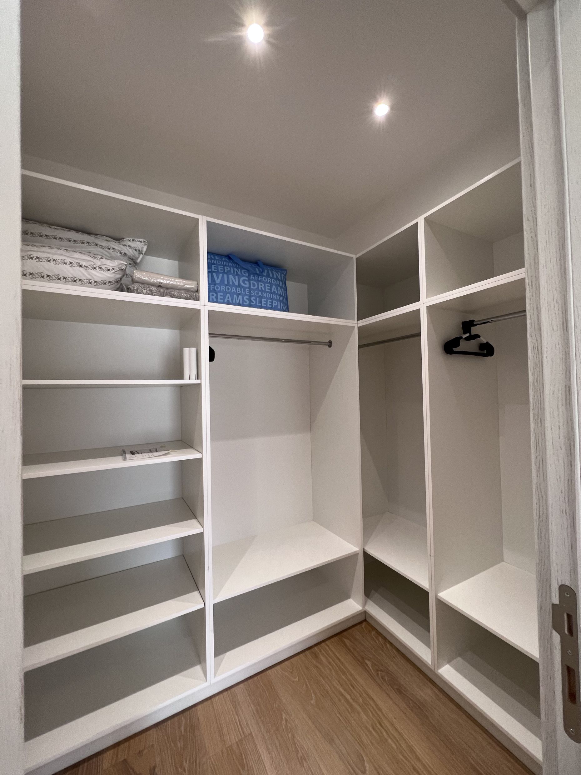 Spacious walk-in closet with white shelves and hanging rods in an apartment, Kotor, Montenegro.