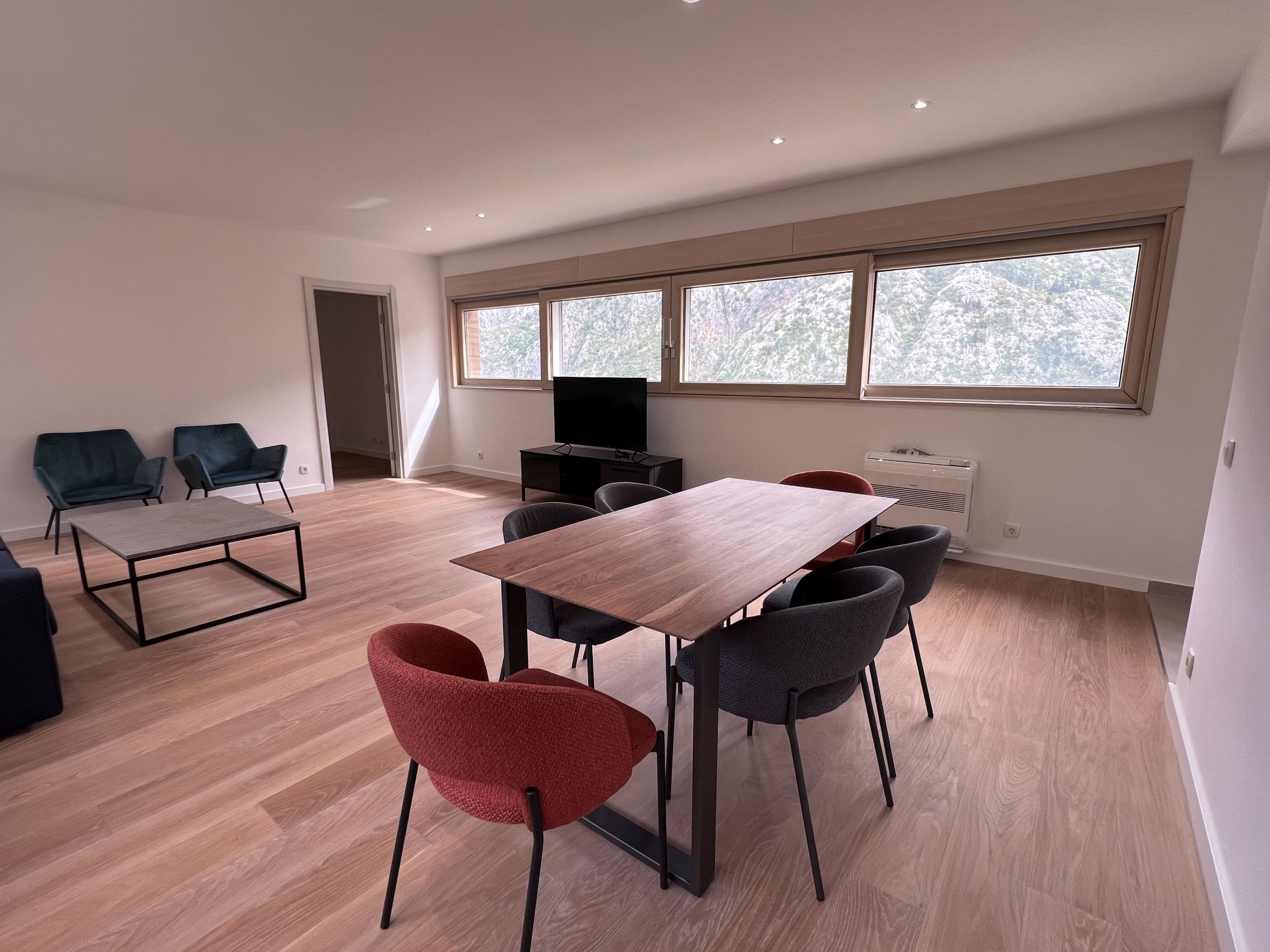Modern living room in an apartment in Kotor, Montenegro: dining area, designer furniture, and panoramic mountain views.