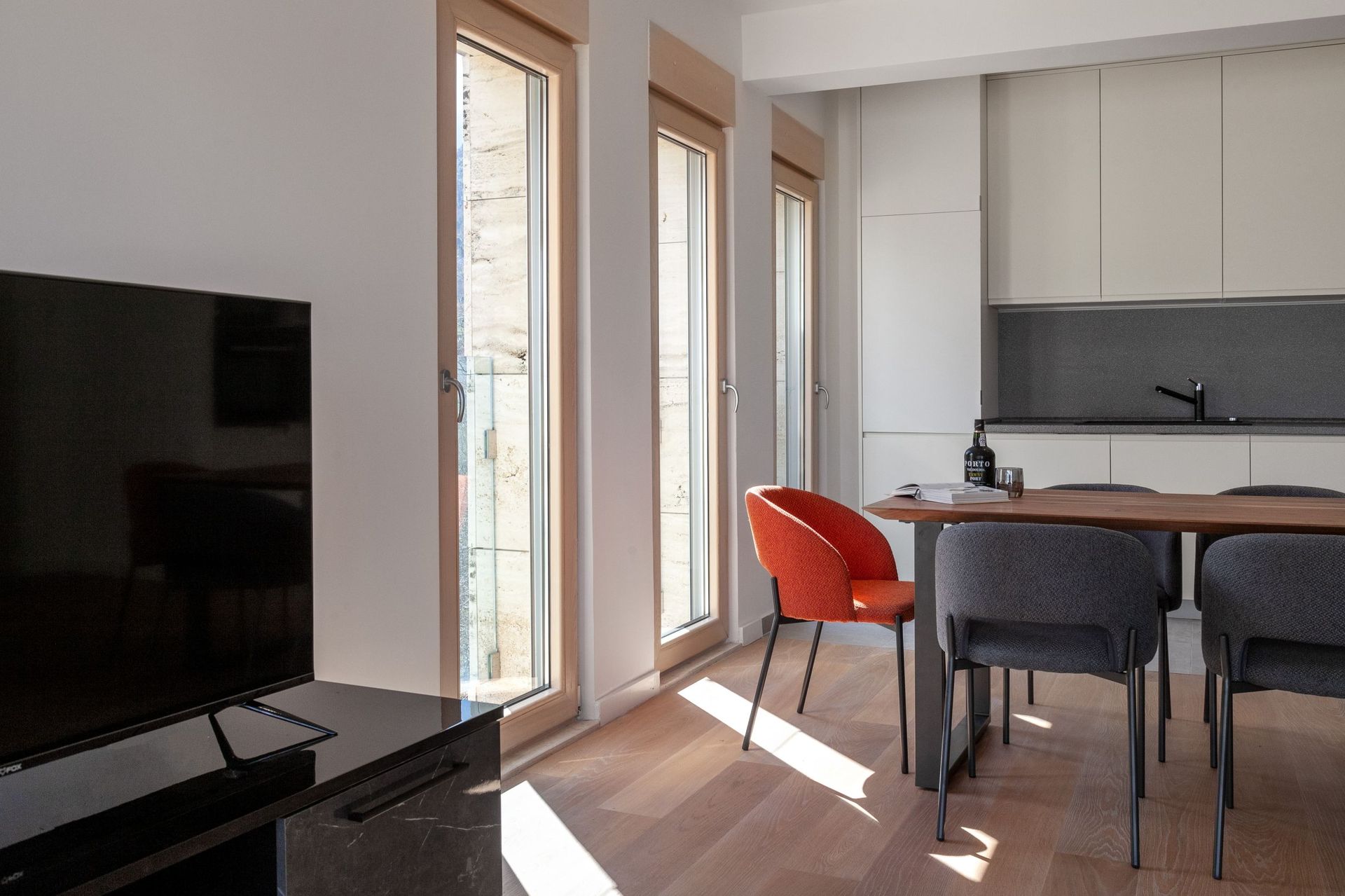 Modern living room with kitchen in an apartment, Kotor, Montenegro: bright interior, wooden floor, and dining area.