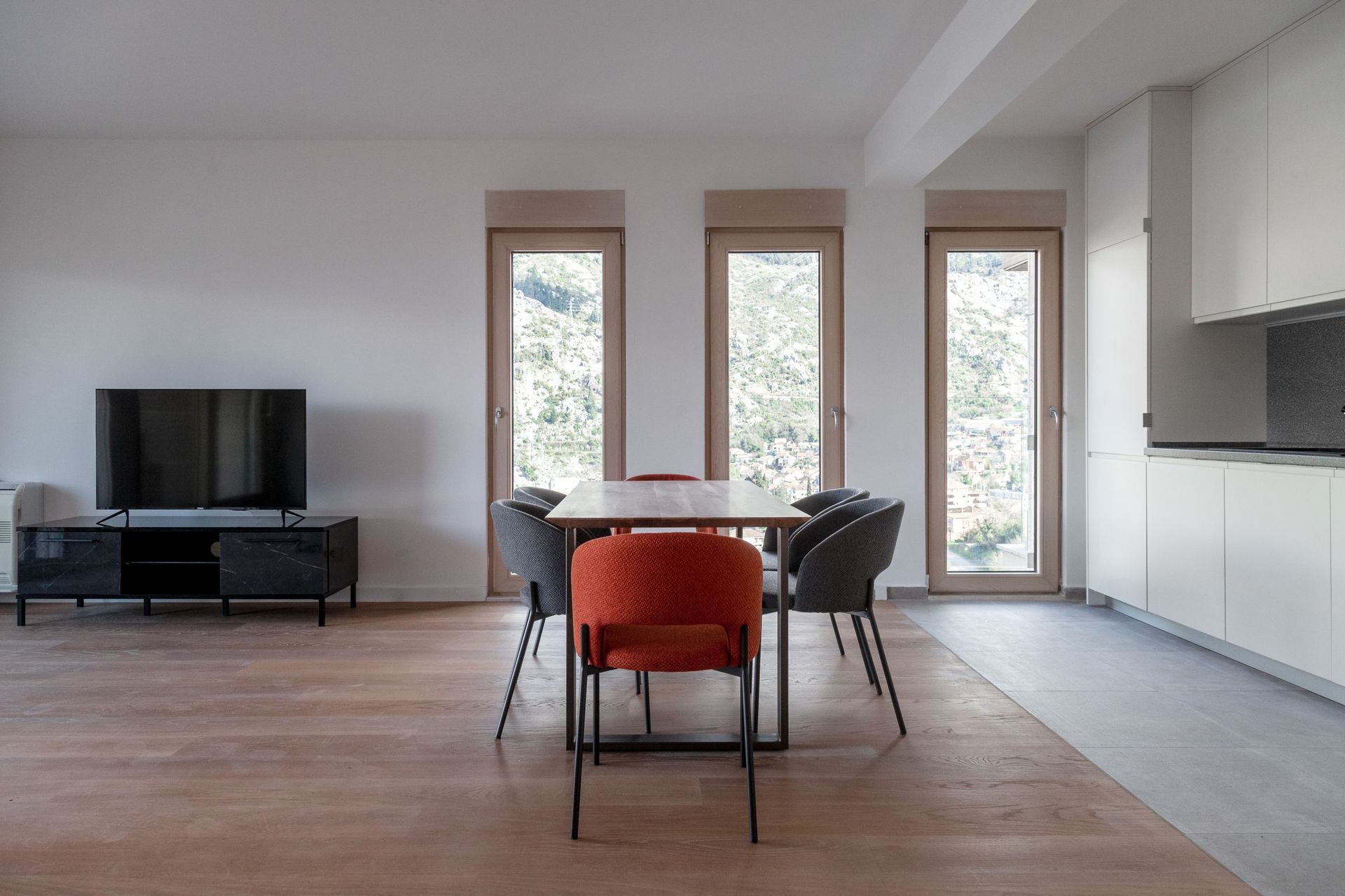 Modern living room with dining area in an apartment, Kotor, Montenegro: mountain view, stylish furniture, and a bright interior.