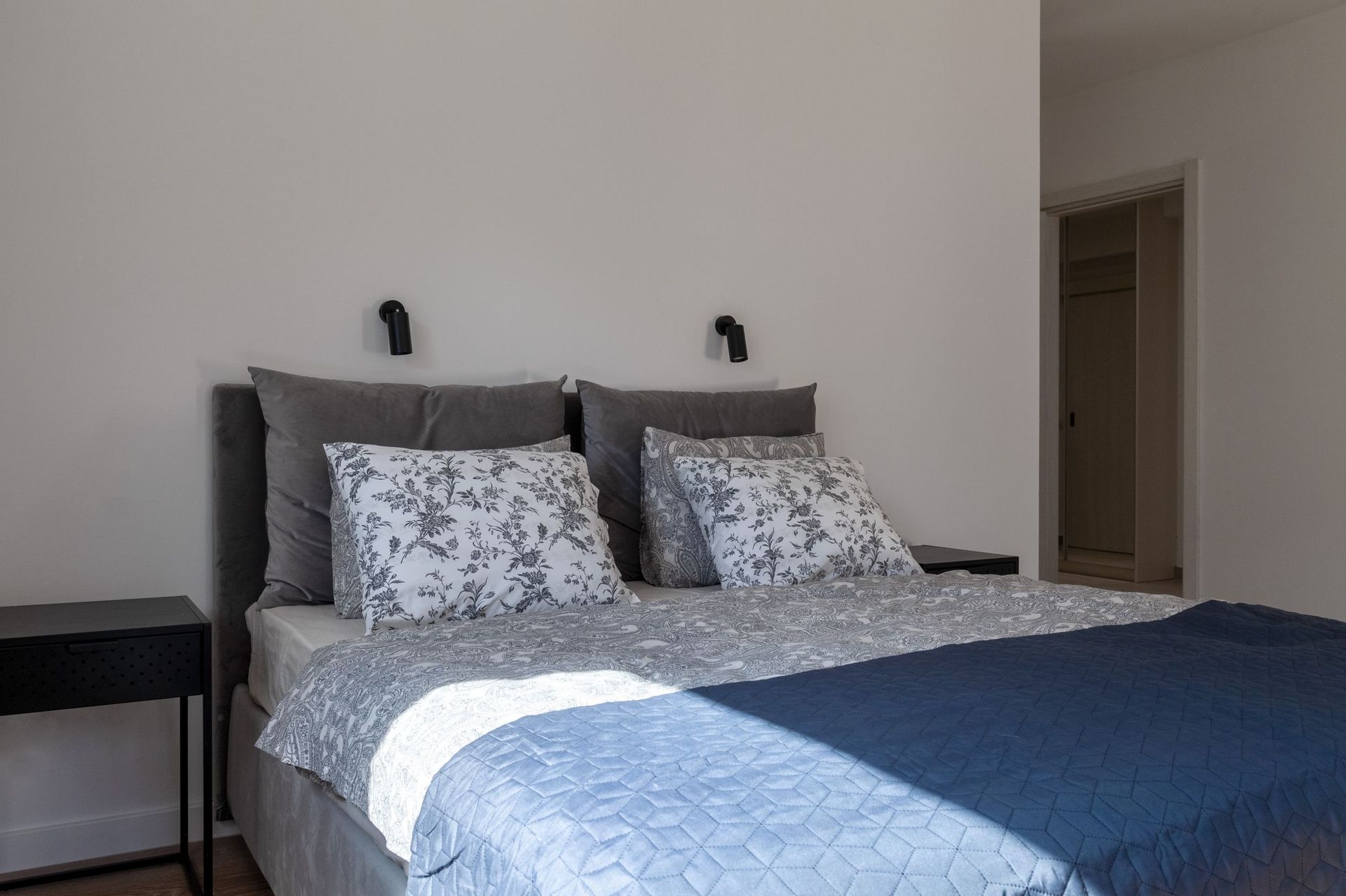 Modern bedroom with a double bed in an apartment in Kotor, Montenegro: gray tones, stylish lighting.