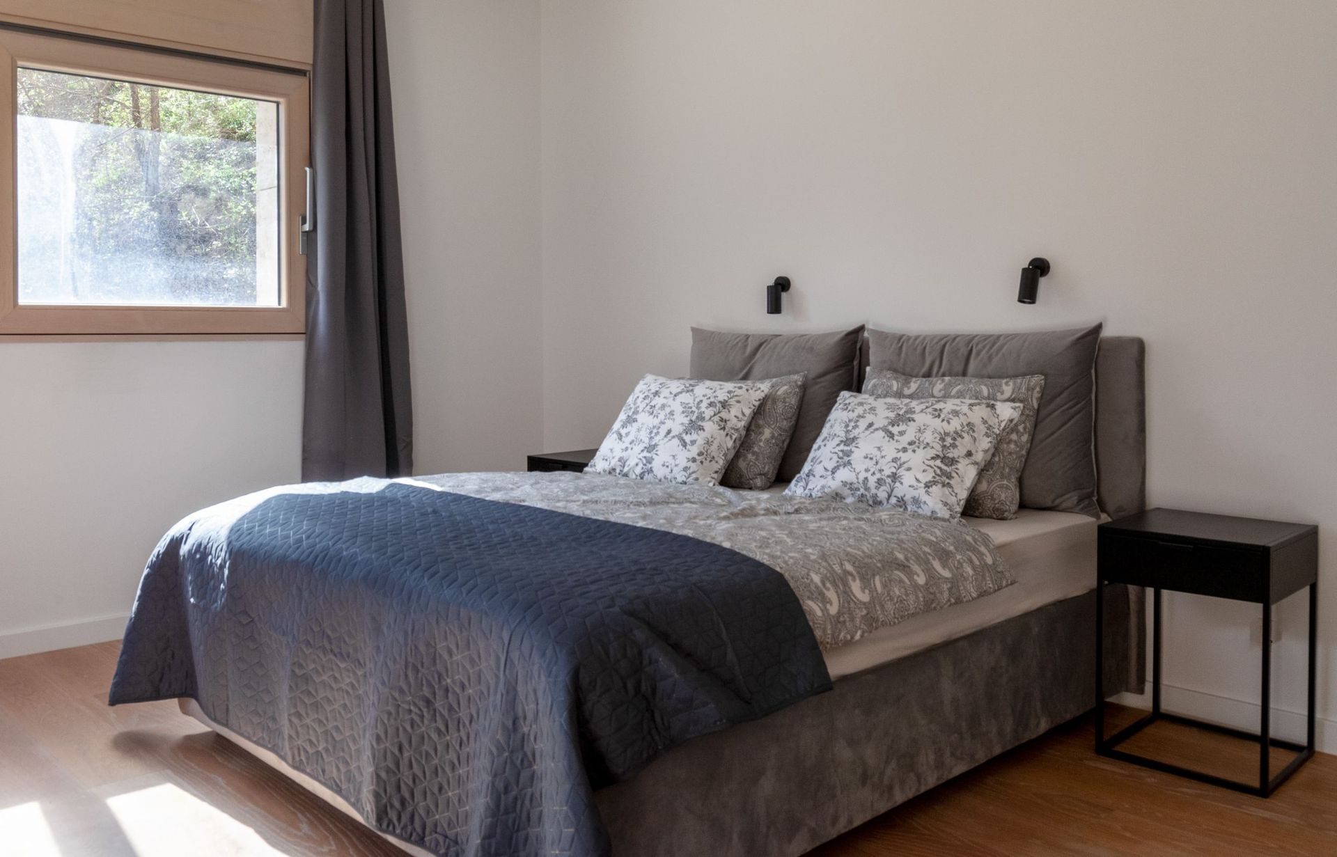 Cozy bedroom with a double bed in an apartment in Kotor, Montenegro: modern furniture and a view of greenery from the window.