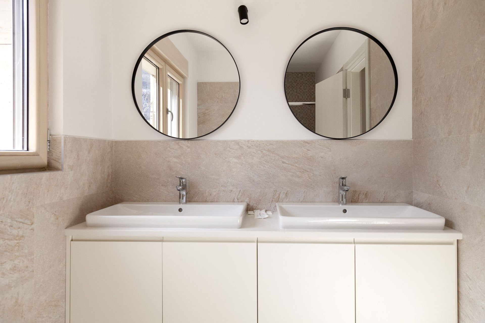 Modern bathroom with two sinks and round mirrors in an apartment, Kotor, Montenegro.