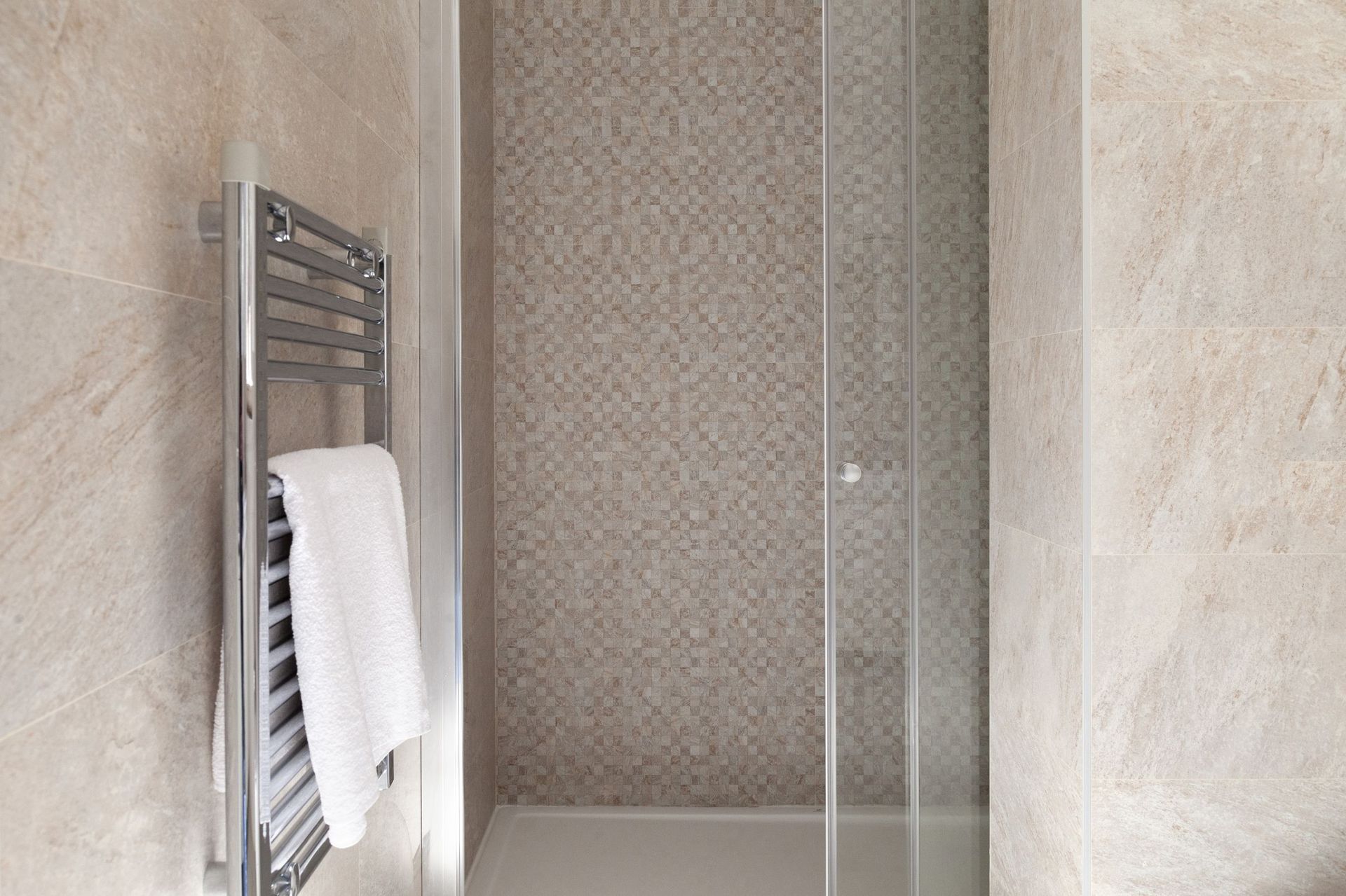 Modern shower cabin with mosaic and towel warmer in an apartment in Kotor, Montenegro.