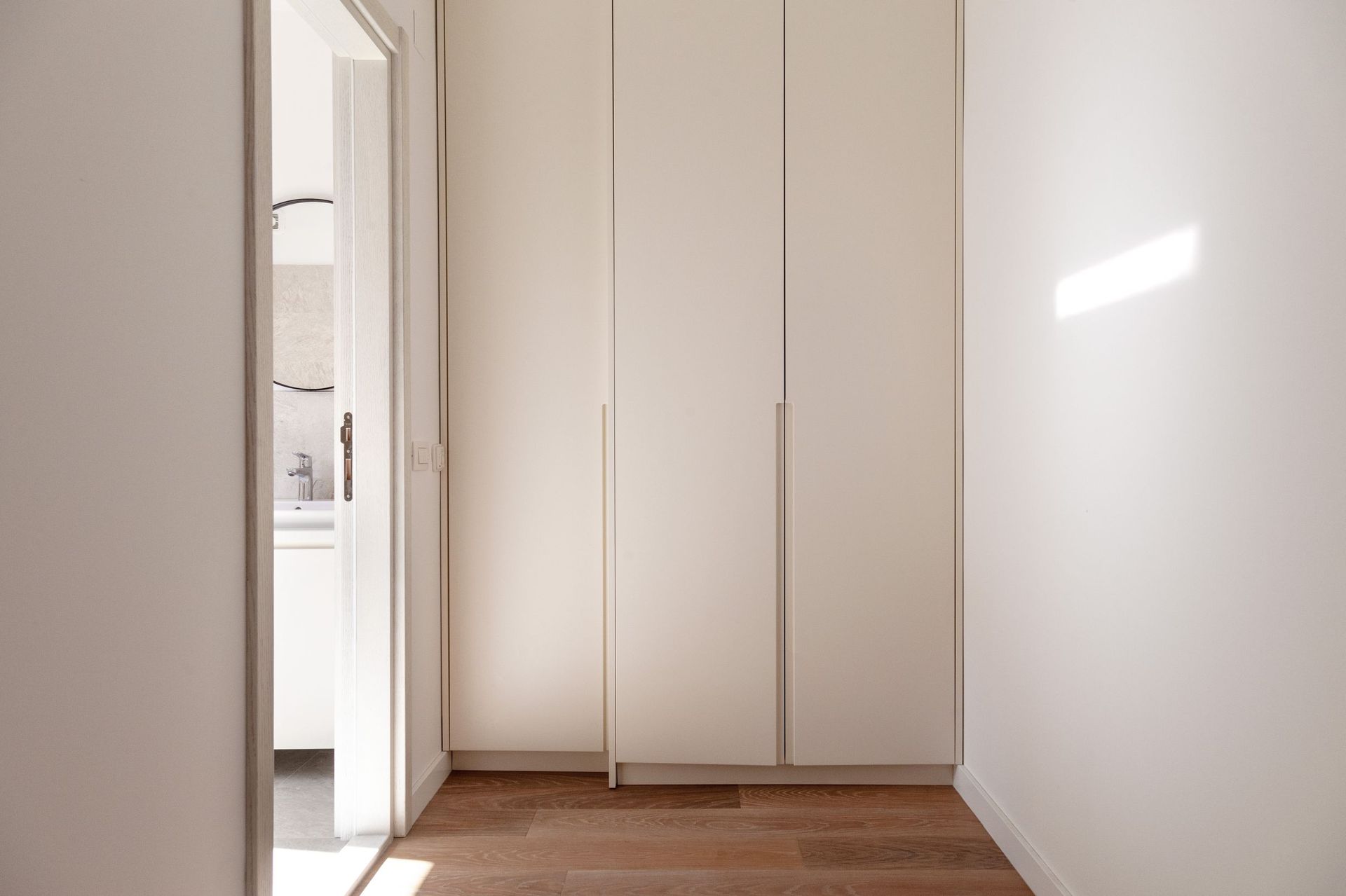 Built-in light-colored closet in the hallway of a modern apartment in Kotor, Montenegro, with a view of the bathroom.