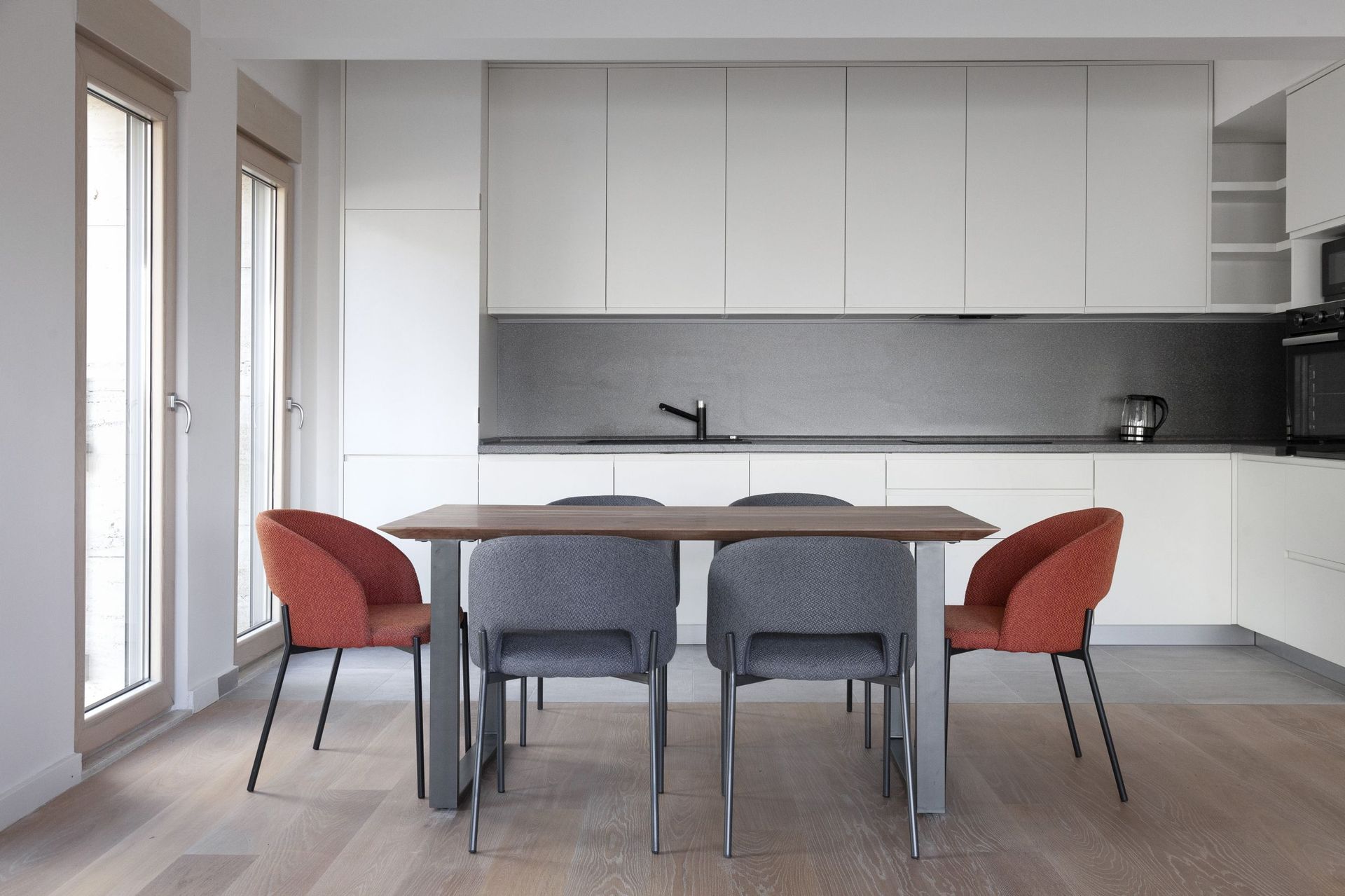 Modern kitchen in an apartment in Kotor, Montenegro: white cabinetry, dining table, and stylish chairs in the interior.