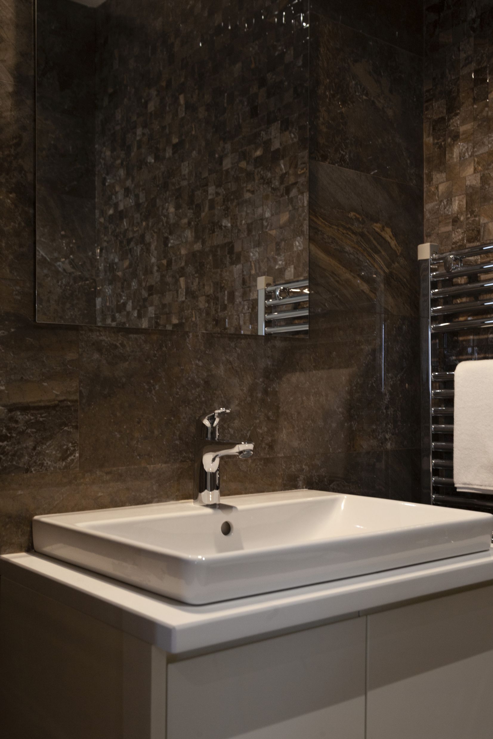 Modern bathroom with dark stone finishes in an apartment in Kotor, Montenegro: sink and mirror.