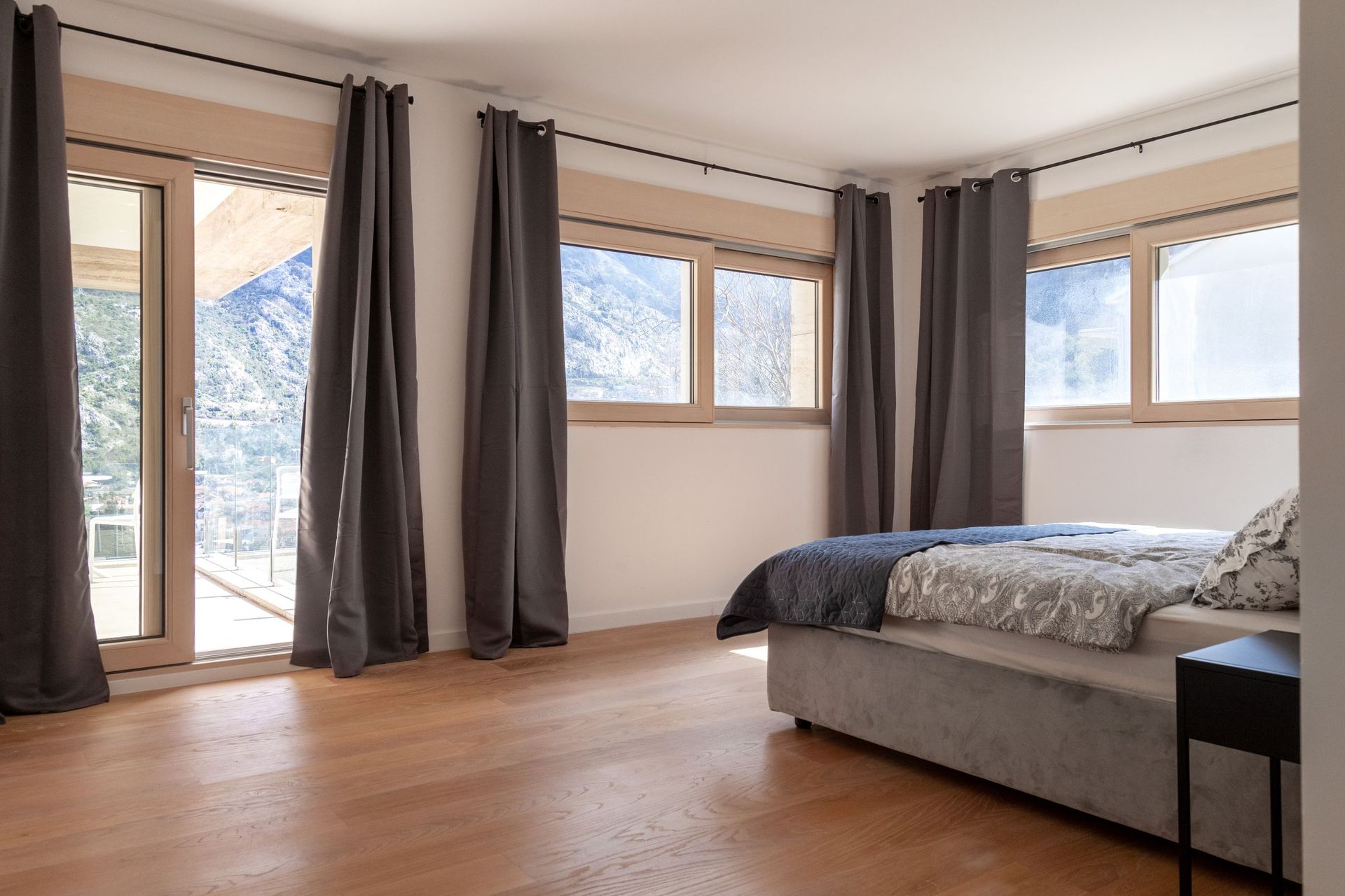 Modern bedroom with a double bed and access to a terrace with mountain views in an apartment, Kotor, Montenegro.