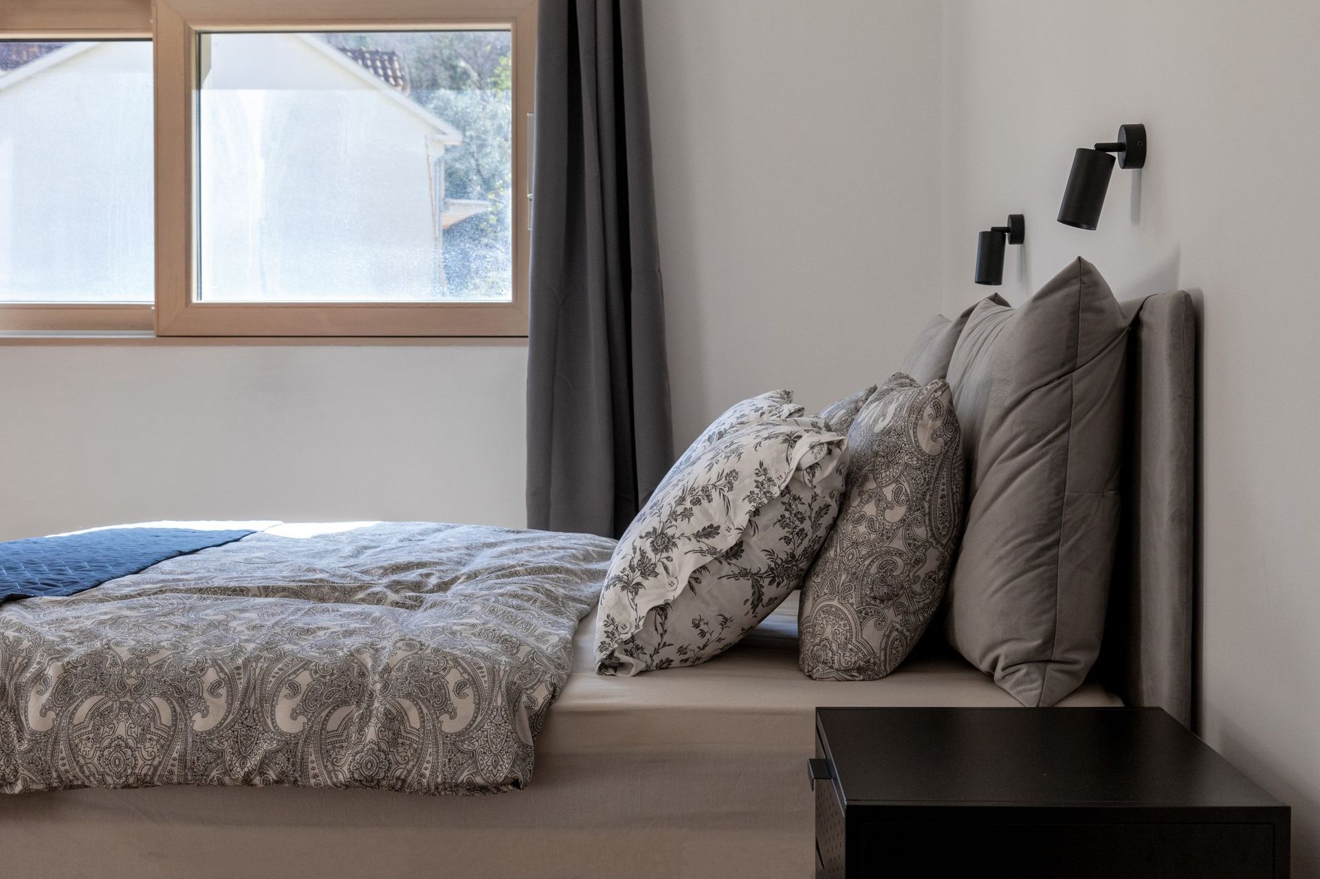 Modern bedroom in an apartment in Kotor, Montenegro: double bed, stylish textiles, and a view from the window.