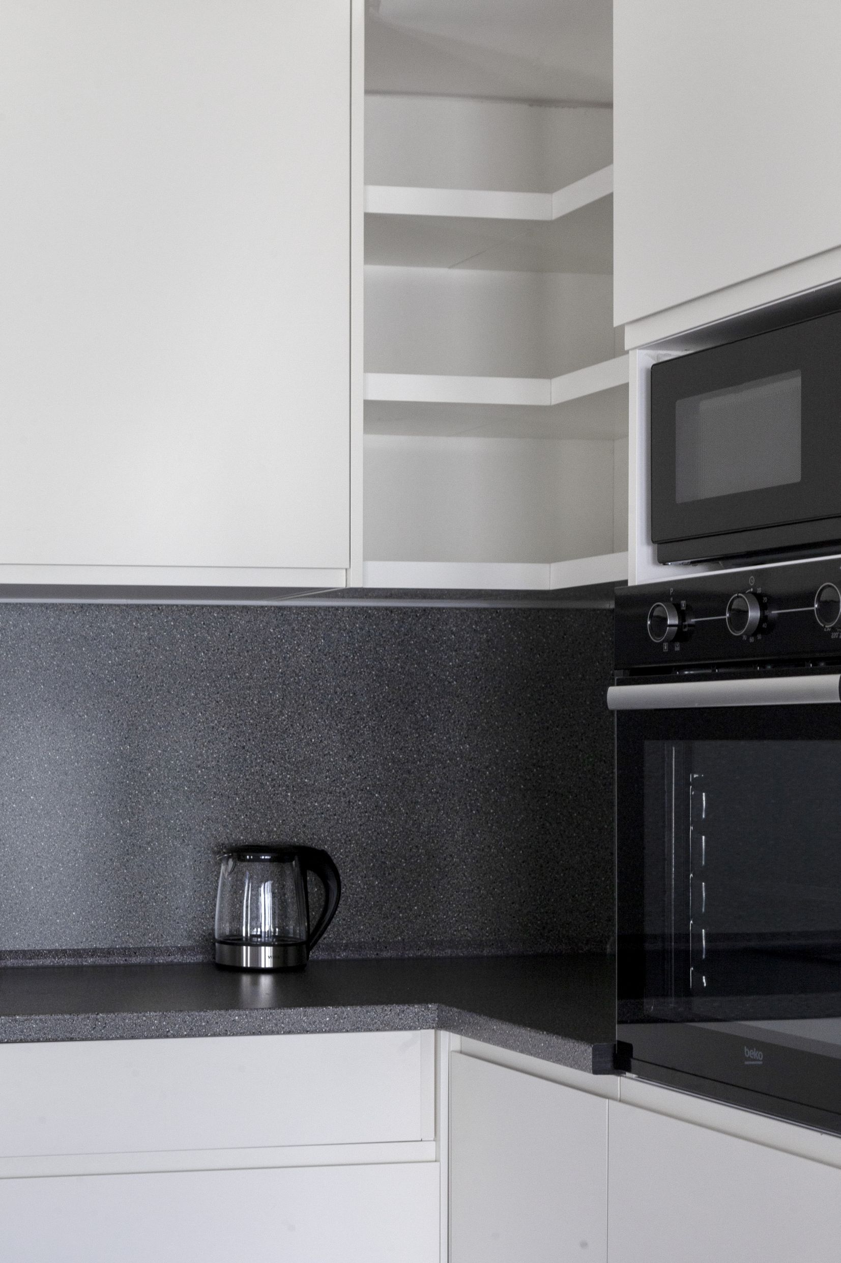 Modern kitchen in an apartment in Kotor, Montenegro: white cabinets, built-in Beko appliances, and a dark countertop.
