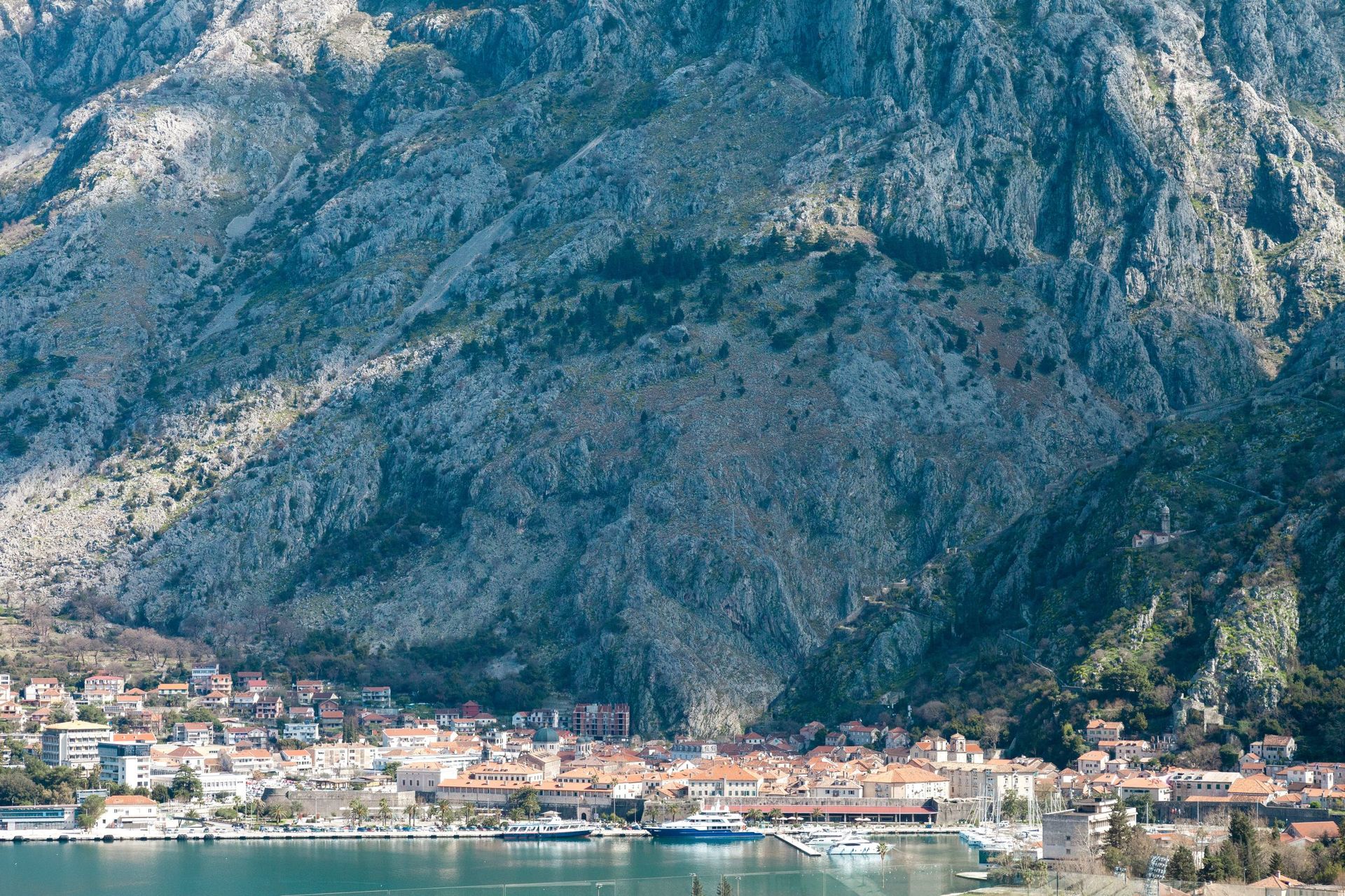 Panoramic view of the city of Kotor and the mountains in Montenegro, overlooking the seaport and historic architecture from the waterfront.