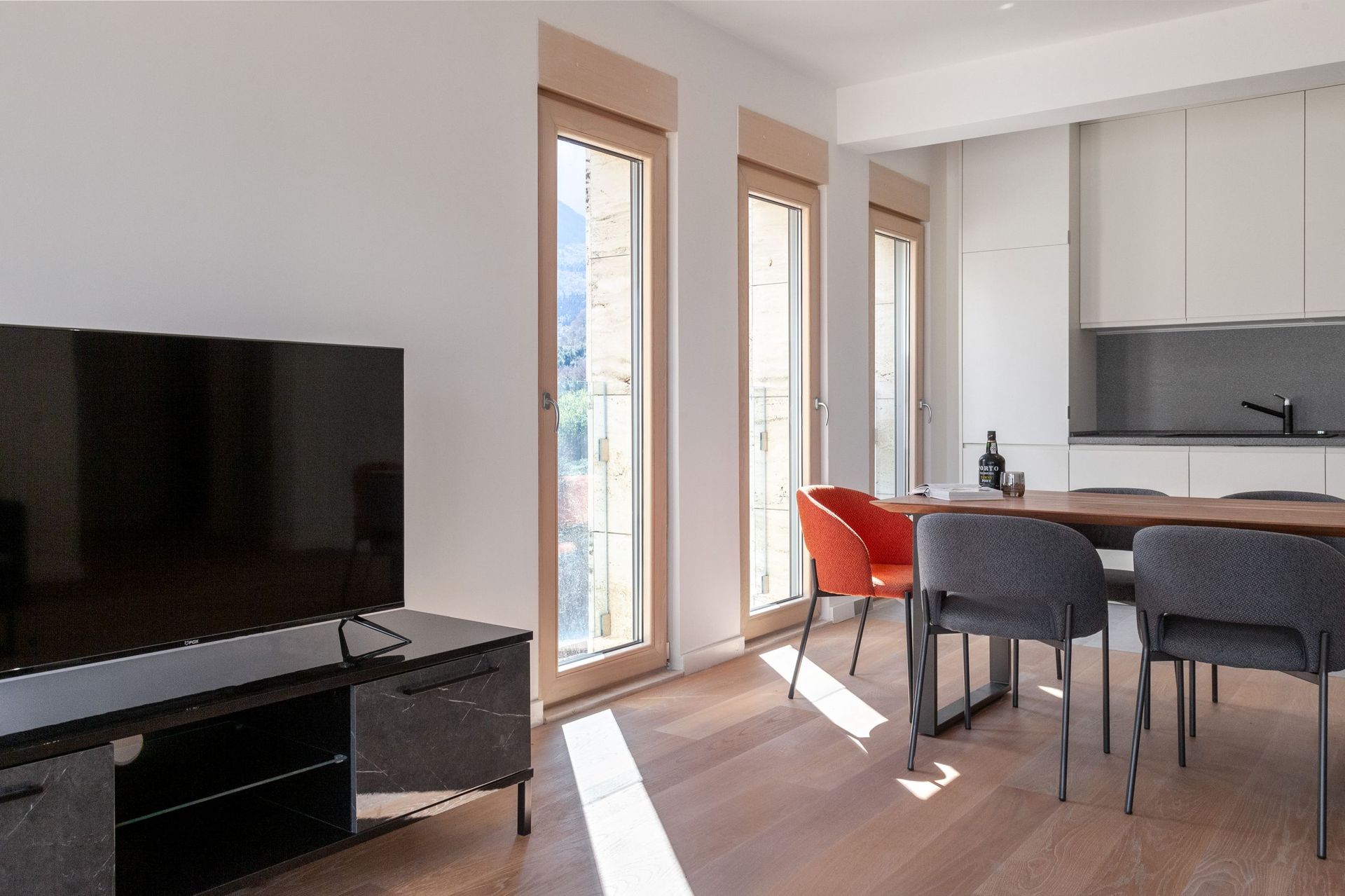 Modern living room with kitchen in an apartment in Kotor, Montenegro: dining area, panoramic windows, and a bright interior.