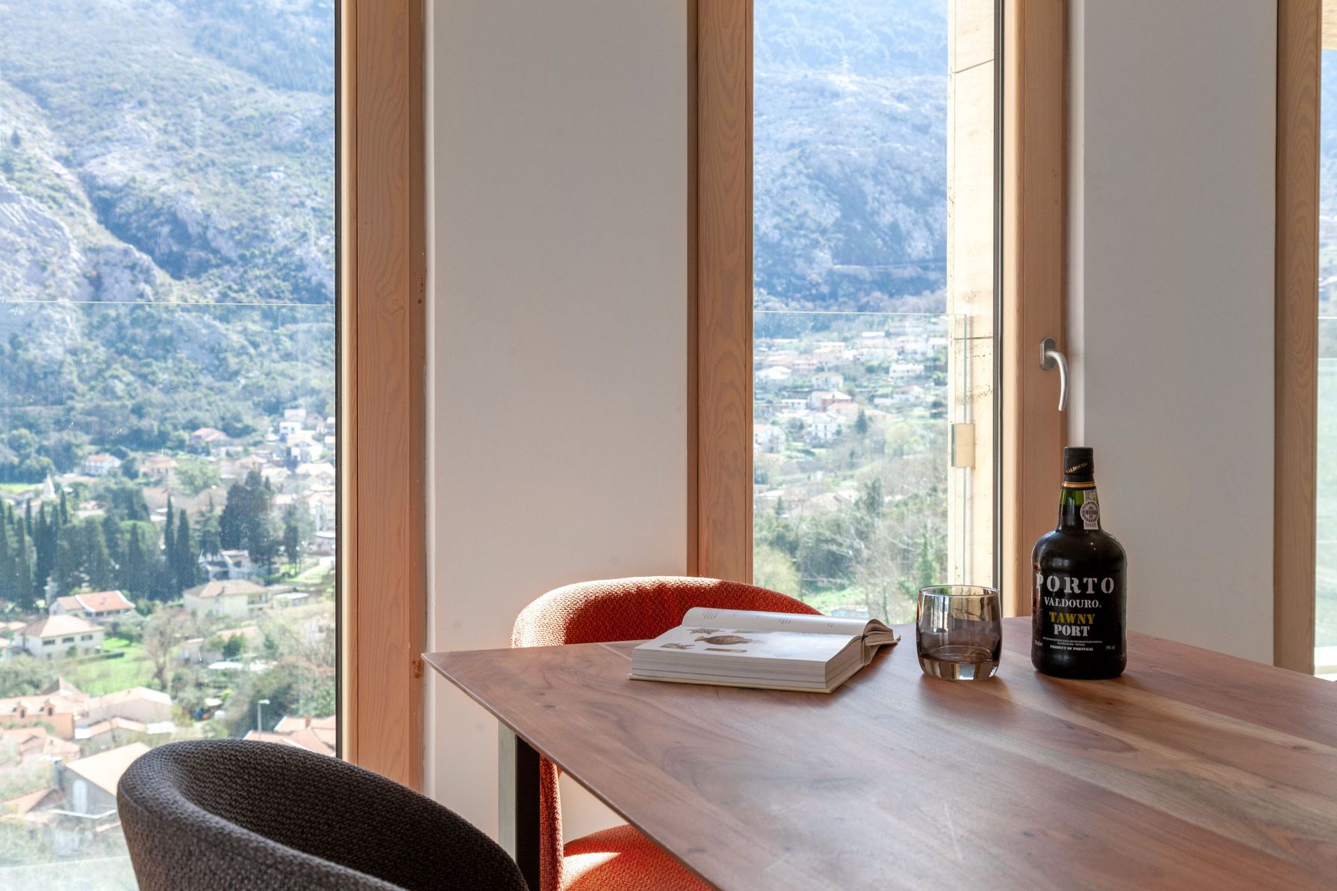 Living room with panoramic views of the mountains and the city of Kotor, Montenegro: a wooden table, stylish armchairs, and a cozy interior.