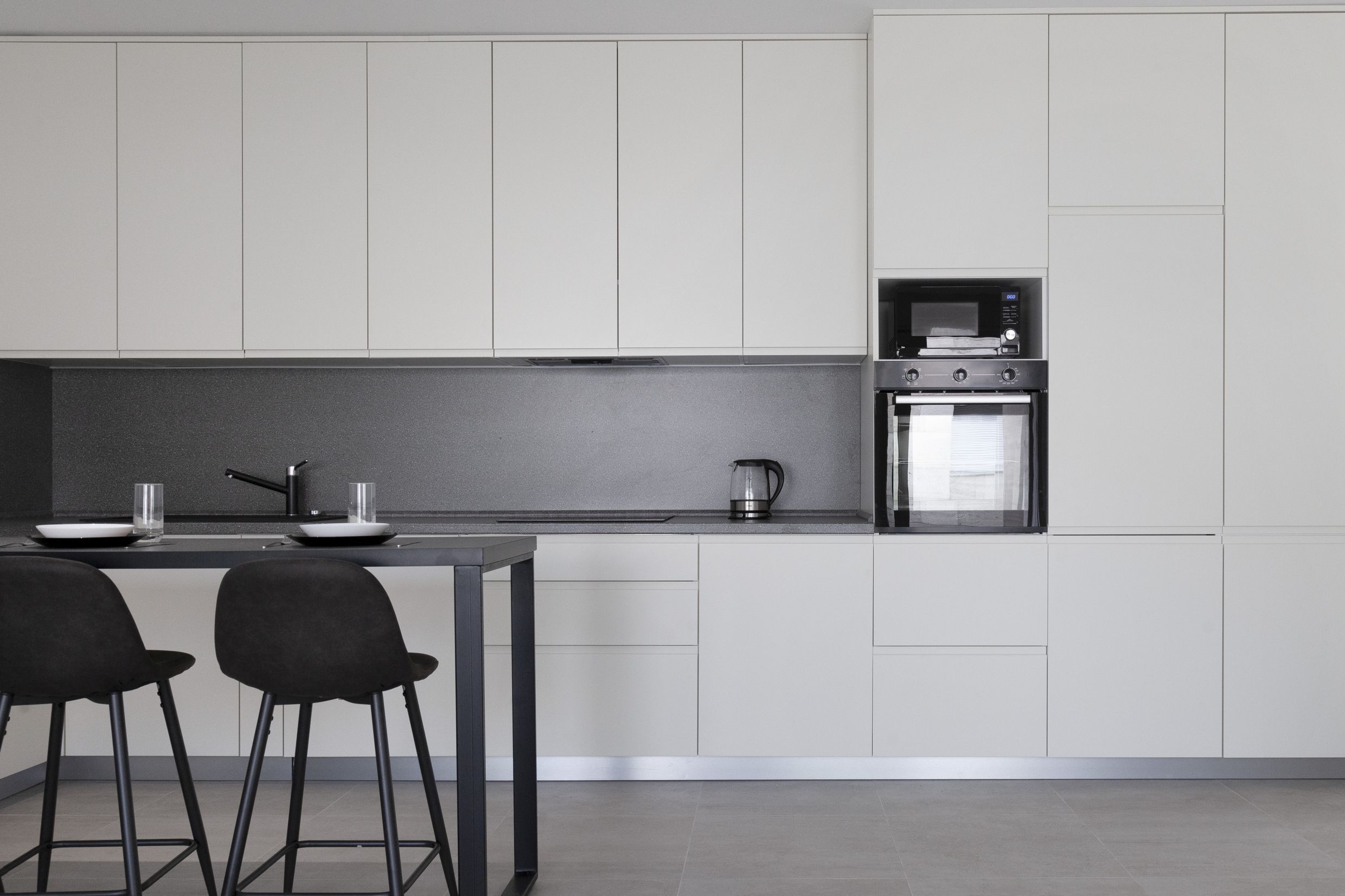 Modern kitchen in an apartment in Kotor, Montenegro: light cabinetry, built-in appliances, and a bar counter with stools.