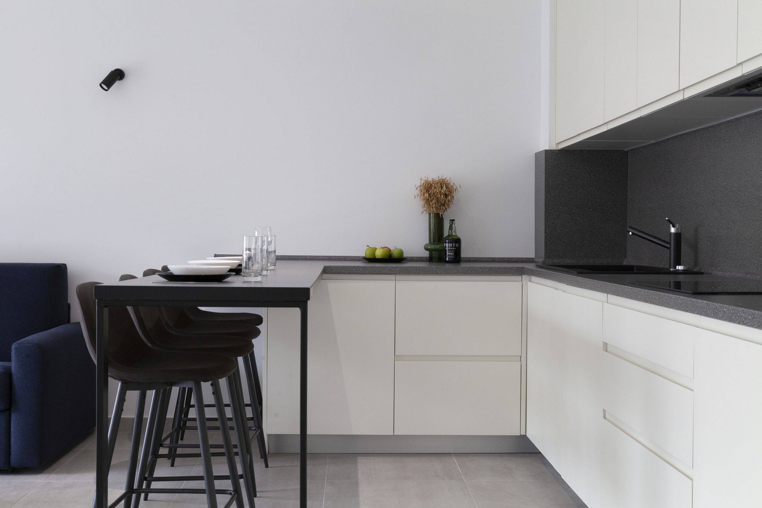 Modern kitchen in an apartment in Kotor, Montenegro: white cabinets, dark countertop, and a breakfast bar with stools.