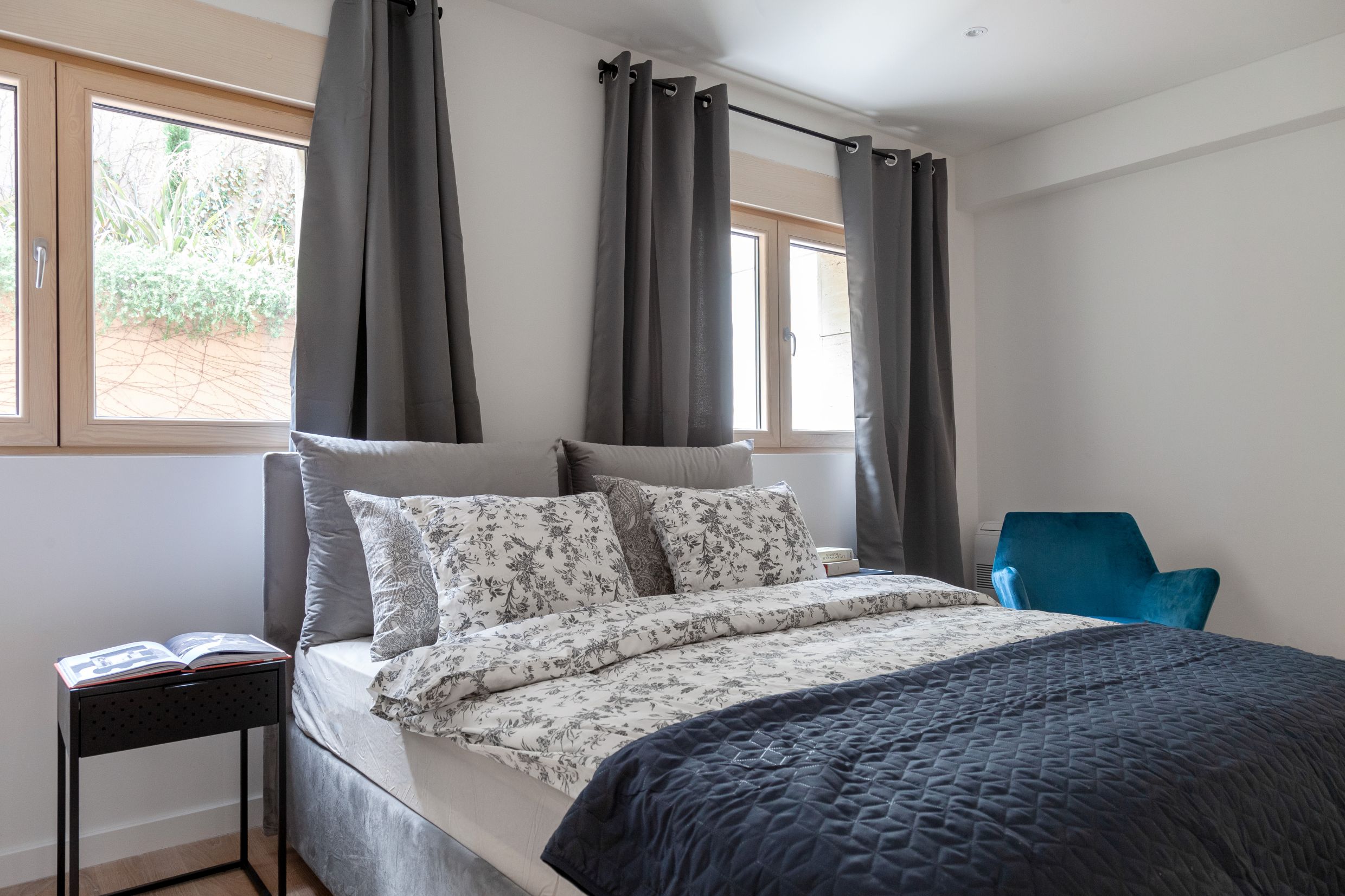 Modern bedroom with a double bed and a blue armchair in an apartment in Kotor, Montenegro.