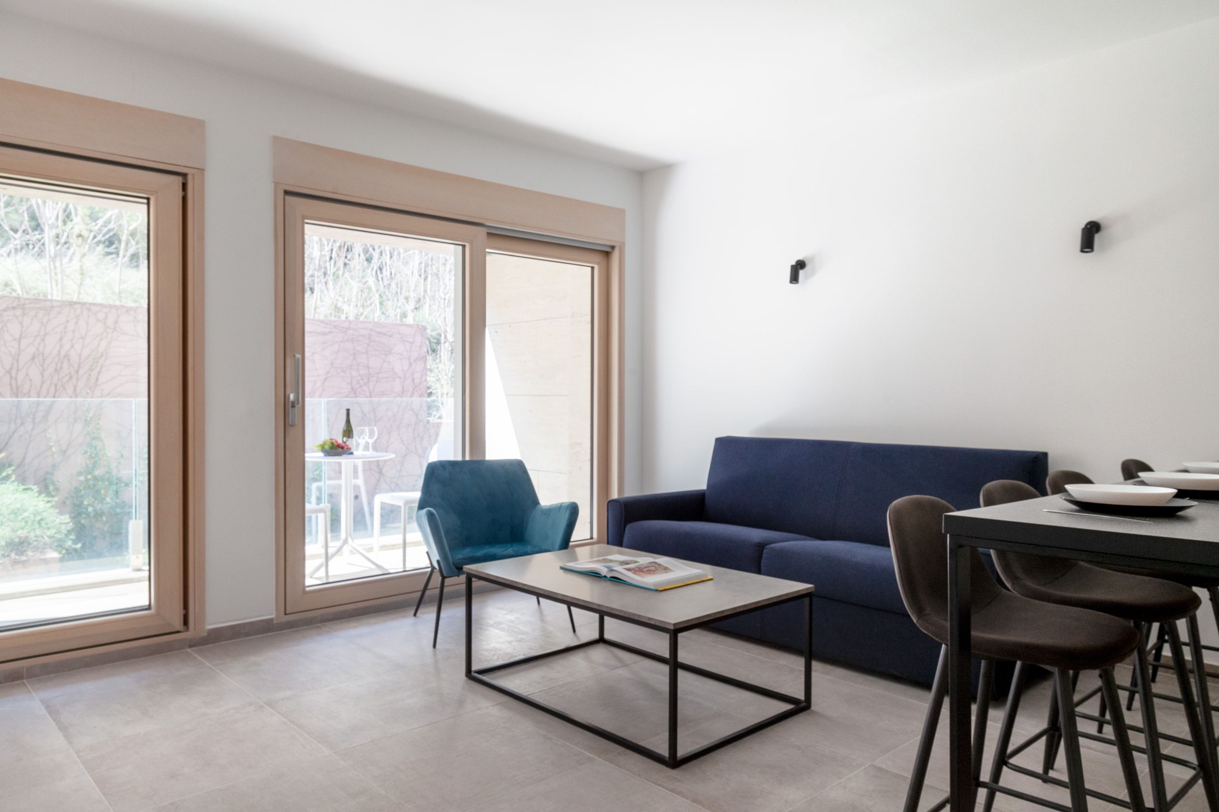Modern living room in an apartment in Kotor, Montenegro: blue sofa, armchair, coffee table, and access to a terrace with a view.