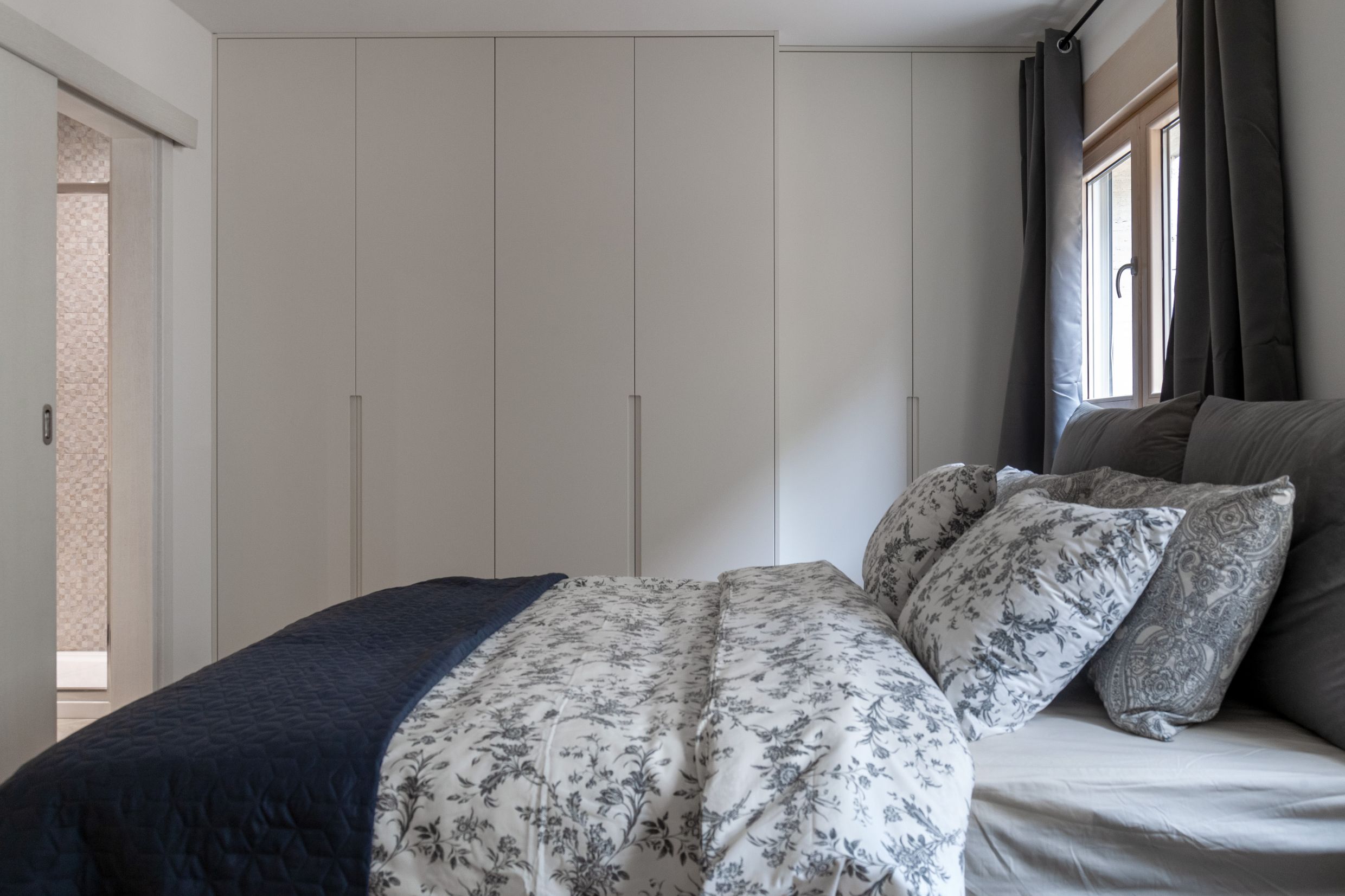 Modern bedroom with a large built-in wardrobe and bed in an apartment, Kotor, Montenegro.