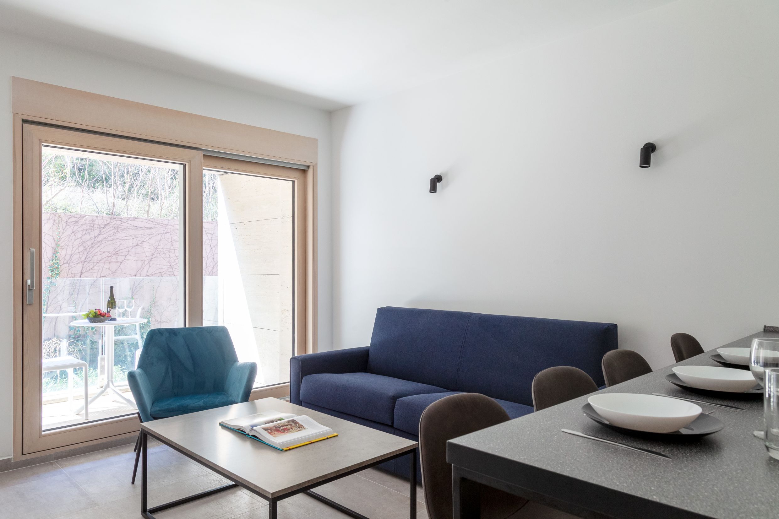 Modern living room in an apartment in Kotor, Montenegro: blue sofa, armchair, dining area, and access to the terrace.