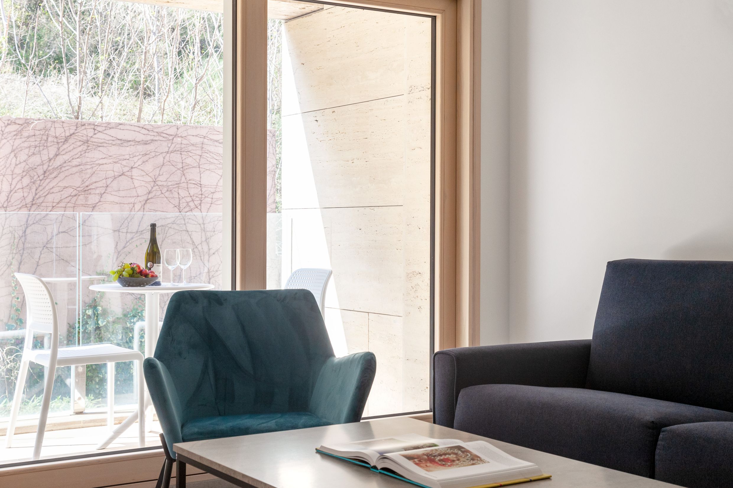 Living room in a modern apartment in Kotor, Montenegro: an armchair, a sofa, and access to a terrace overlooking the garden.