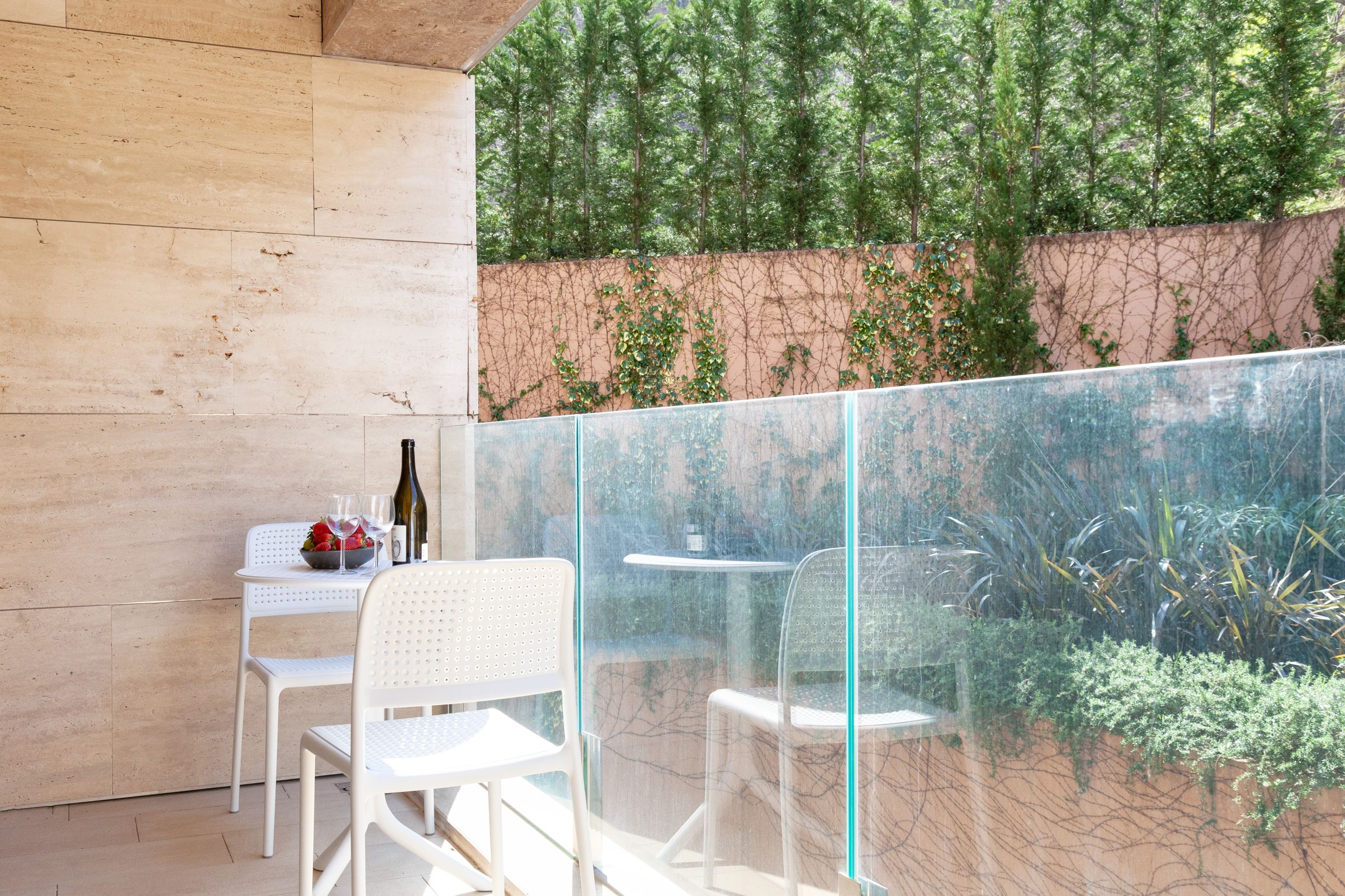Cozy balcony with white furniture and a view of the garden in an apartment in Kotor, Montenegro. Walls finished with natural stone.
