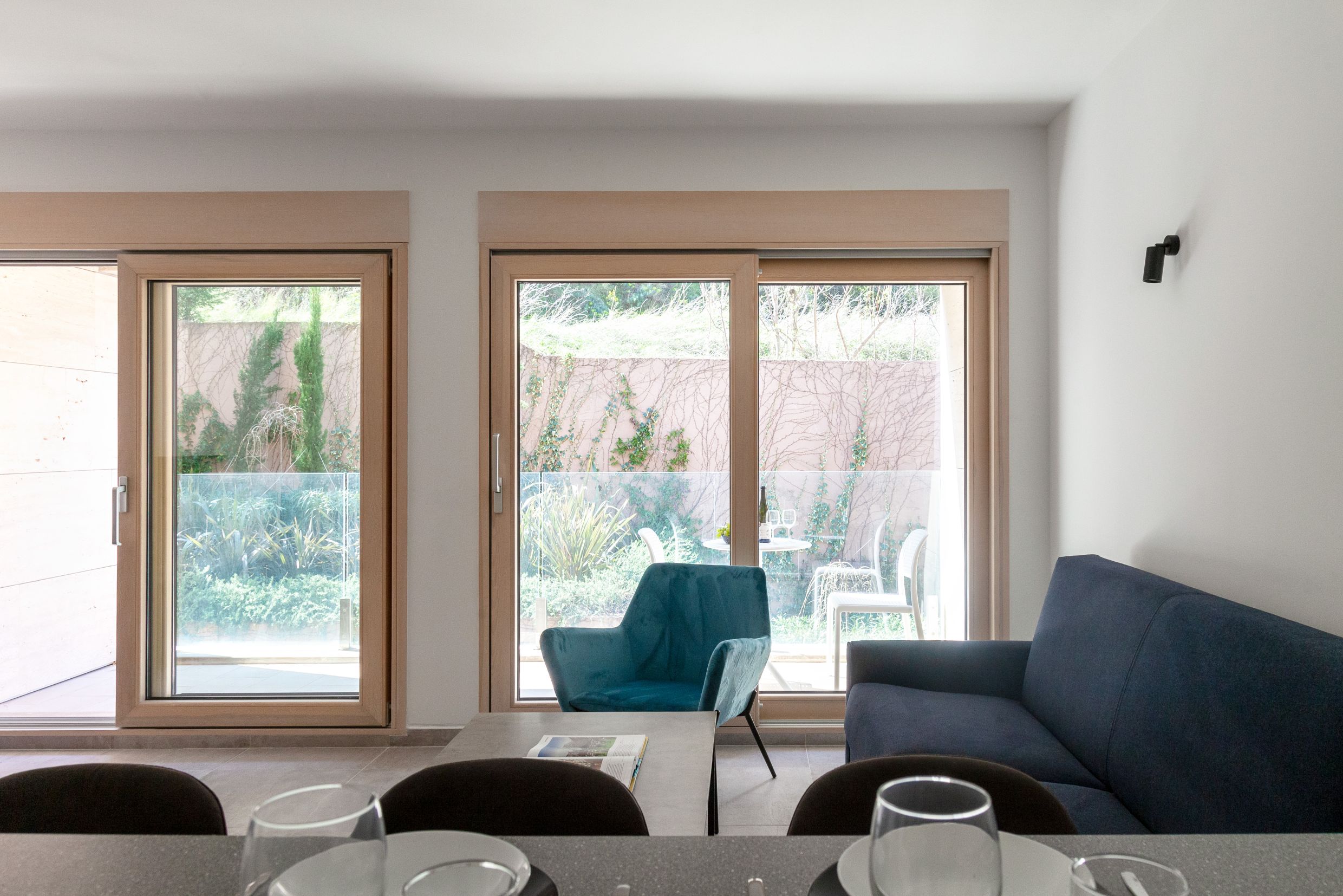 Living room in an apartment in Kotor, Montenegro: modern furniture, panoramic windows, and access to a terrace with a garden.