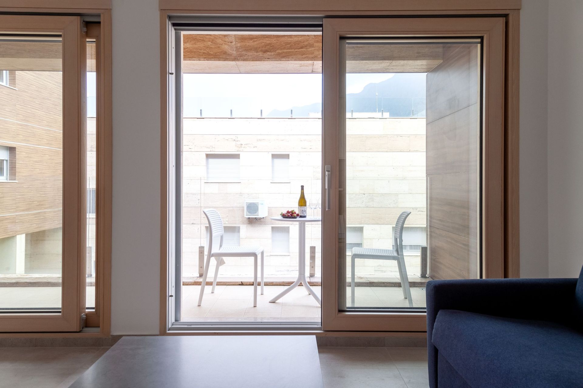 View from the living room onto a furnished terrace in a modern apartment in Kotor, Montenegro. Panoramic windows and a bright interior.