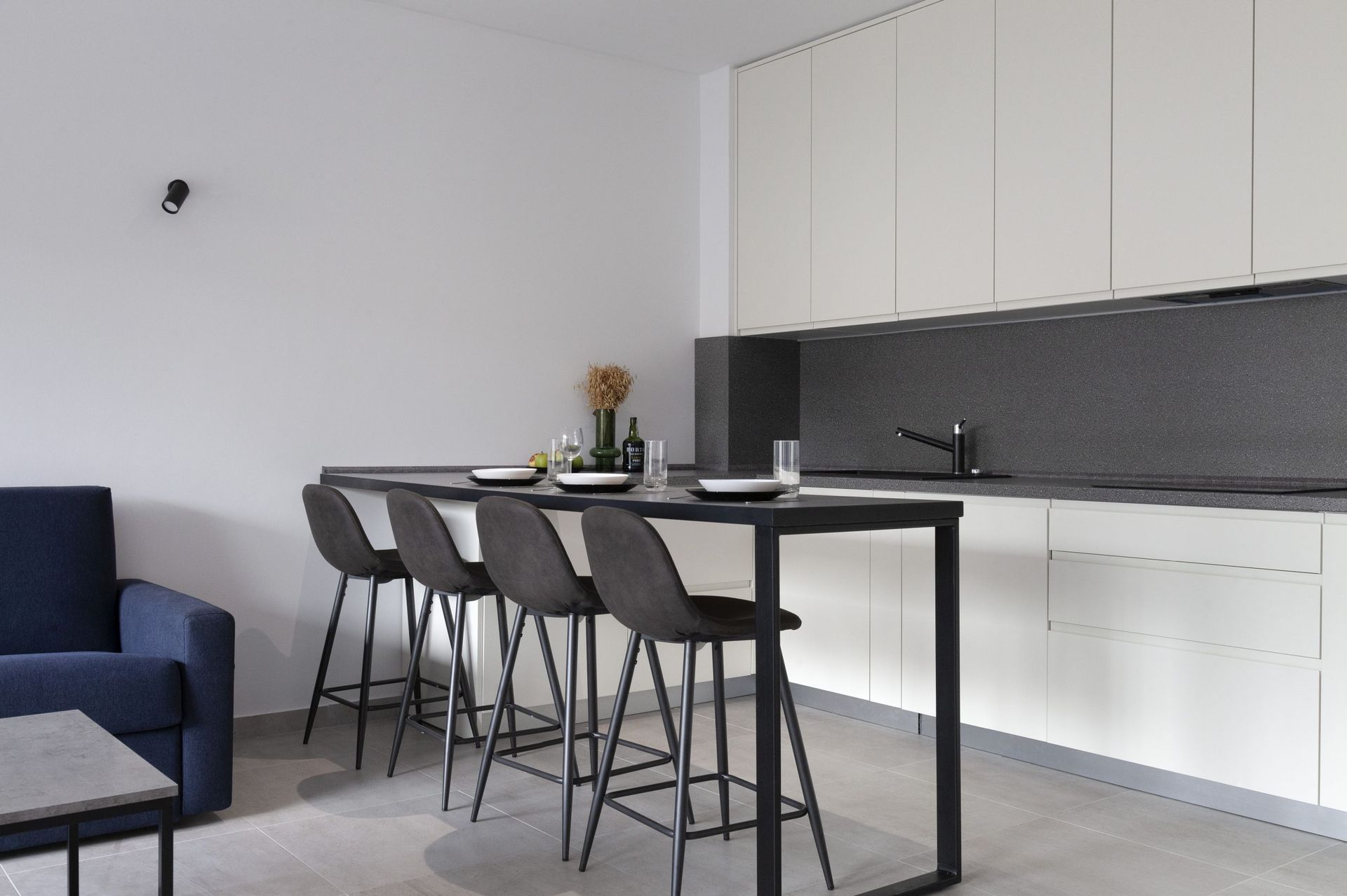 Modern kitchen in an apartment in Kotor, Montenegro: white cabinets, dark countertop, and a bar counter with high stools.